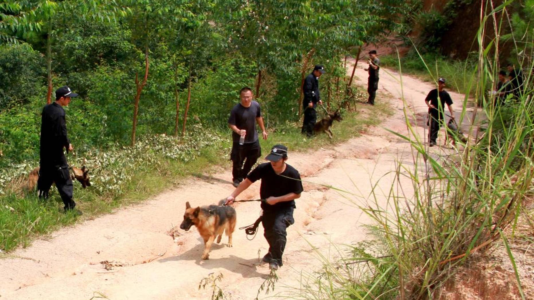 In this photo released by China's Xinhua news agency, policemen use sniffer dogs to search for a man of stabbing four elementary school students, in Pingshan Town of Lingshan County, south China's Guangxi Zhuang Autonomous Region, Friday, Sept. 26, 2014. The man fatally stabbed four elementary school students Friday while they were on their way to school, the latest of several slashing attacks targeting schoolchildren over the past decade. The county government said on its website that three of the children were killed instantly and that one died later in hospital. Officials said police are searching for 56-year-old suspect, but gave no other details. (AP Photo/Xinhua, Zhang Ailin) NO SALES
