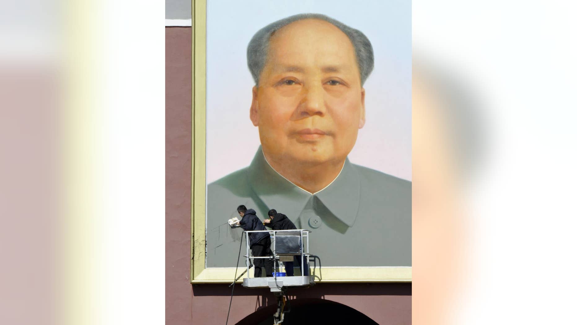 In this March 6, 2014 file photo, workers clean black marks off the portrait of late communist leader Mao Zedong which hangs on Tiananmen Gate in Beijing, China.