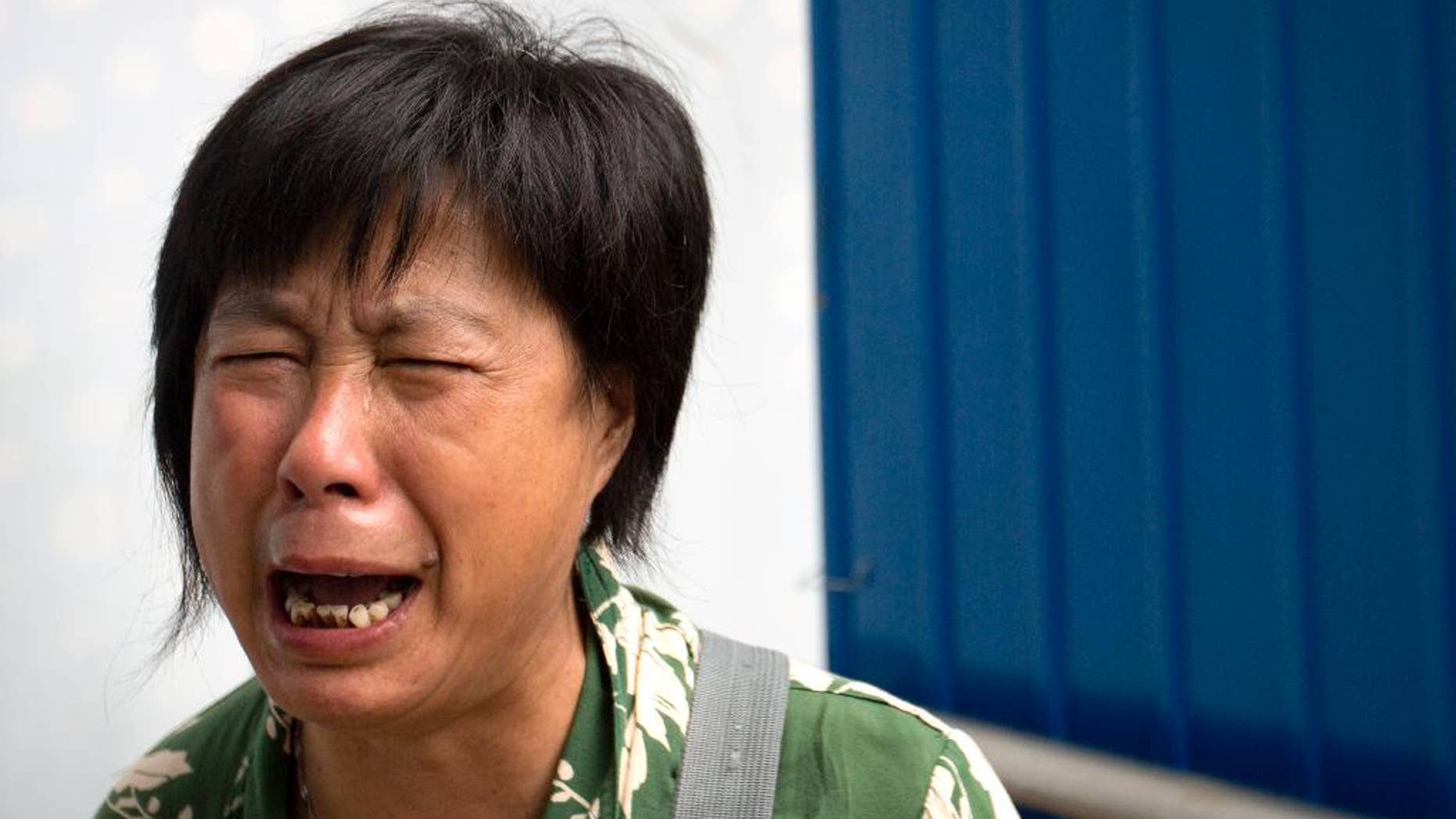 Bao Lanfang, whose daughter-in-law, son, and granddaughter were aboard Malaysia Airlines Flight 370, cries as she protests outside the company's offices in Beijing, Thursday, Aug. 6, 2015. About a dozen Chinese relatives of passengers protested outside the Malaysia Airlines offices in Beijing on Thursday. Families aching for closure after their relatives disappeared aboard Malaysia Airlines Flight 370 last year vented their deep frustration Thursday at conflicting signals from Malaysia and France over whether the finding of a plane part had been confirmed. (AP Photo/Mark Schiefelbein)