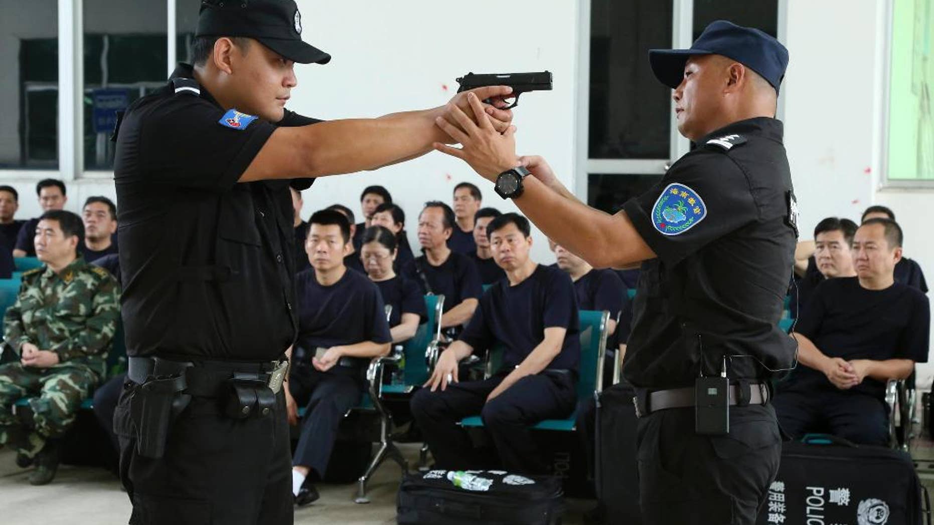 FILE - In this April 25, 2014 file photo, a police training officer, right, guides a trainee during a weapons training session for police officers in Haikou, in southern China's Hainan province. Newly granted power for normal Chinese police officers to carry a firearm, has raised calls for a full independent investigation, after a police officer killed an unarmed traveler in front of his elderly mother and three small children at a train station, the Public Security Ministry said Tuesday May 12, 2015, after several shootings by police were never fully accounted for, according to Zhao Chu, a Shanghai-based independent commentator. (Chinatopix via AP, File) CHINA OUT