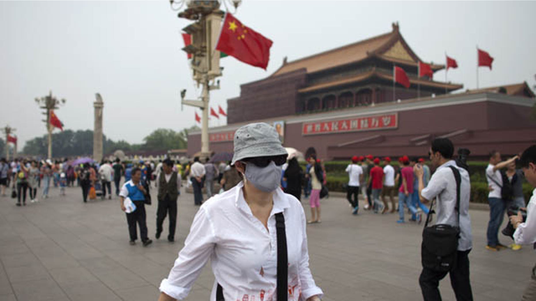 FILE - In this May 7, 2013 file photo, a foreign tourist wearing a mask walks in front of Tiananmen Gate on a polluted day in Beijing, China. (AP Photo)