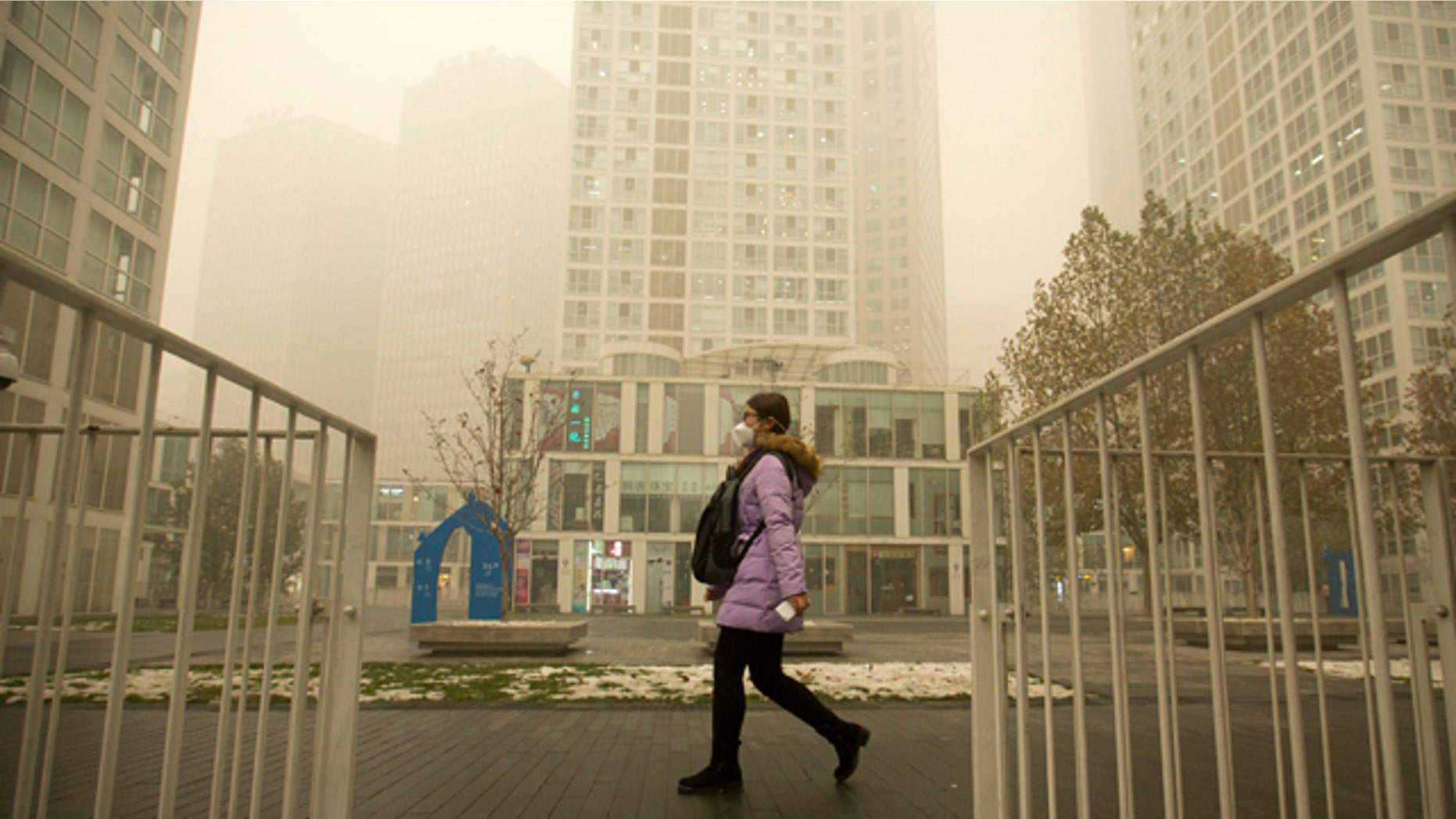 Dec. 1, 2015: A woman wearing a face mask walks through a shopping and office complex amid heavy pollution and fog in Beijing. (AP Photo/Mark Schiefelbein)