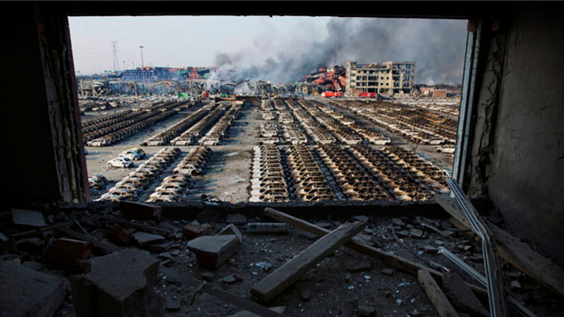 FILE - In this Aug. 13, 2015 photo, a shattered window frames the site of an explosion at a port warehouse in northeastern China's Tianjin municipality. (AP Photo/Ng Han Guan. File)