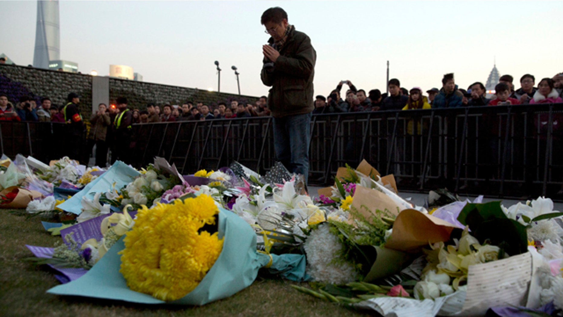 FILE - In this Thursday, Jan. 1, 2015 file photo, a man prays after laying flowers at the site of a New Years Eve deadly stampede in Shanghai. (AP Photo/Ng Han Guan, File)