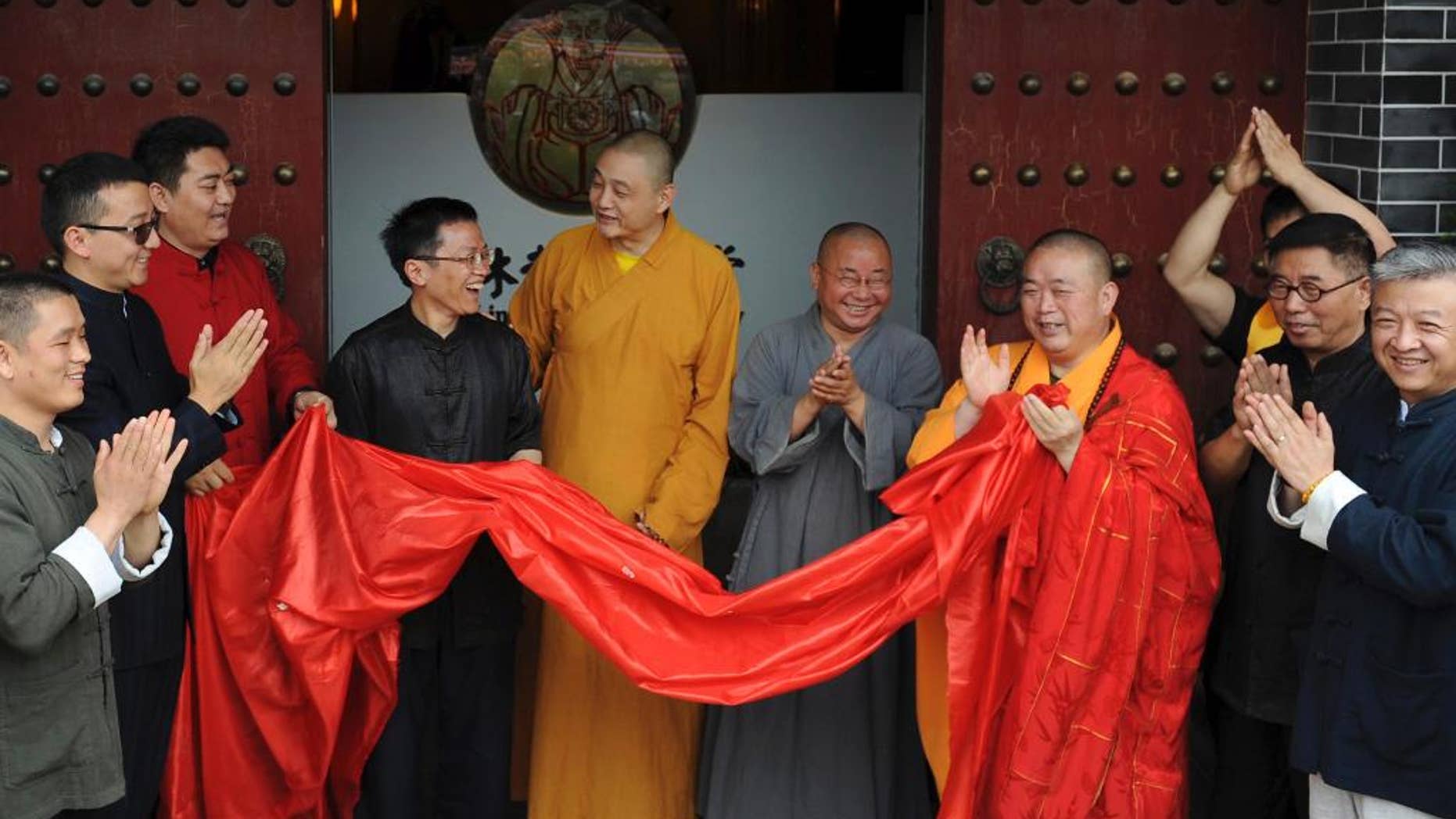 In this photo taken Sunday June 28, 2015, Shi Yongxin, third from right in yellow and red robes, abbot of the Shaolin Temple, attends the opening ceremony of an urban zen center named Shaolin Chan Hall in Xi'an in northwest China's Shaanxi province. Chinese authorities are investigating allegations of misbehavior made online against the controversial abbot of China's famed Shaolin Temple. (Chinatopix Via AP) CHINA OUT