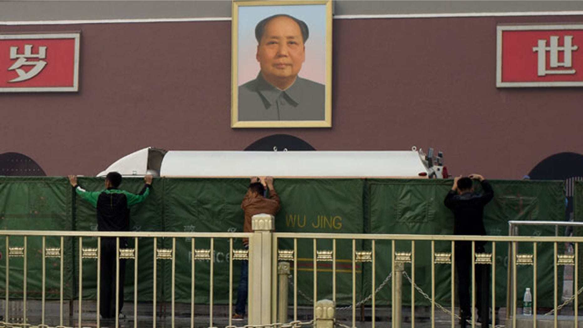 October 28, 2013: Plainclothes policemen place green net shields in front of Tiananmen Gate following a car fire in Beijing. (AP Photo)