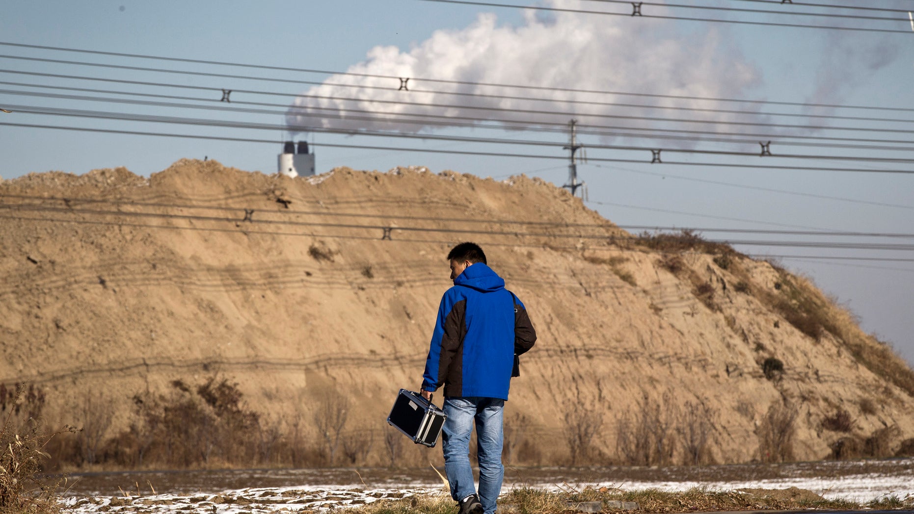 Dec. 3, 2011: Tan Liang, a resident carries a PM2.5 detector walks towards a garbage-burning facility, located near his residential compound in Beijing, China.