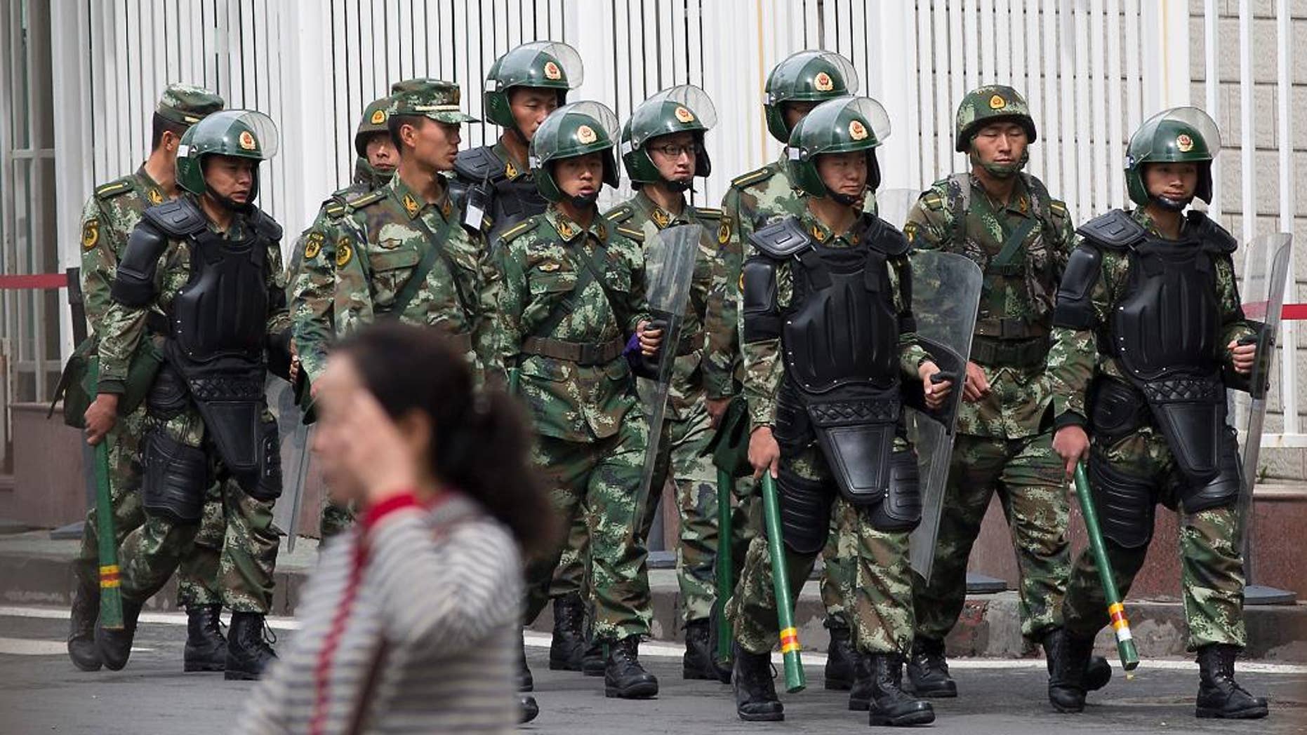 FILE - In this May 23, 2014 file photo, paramilitary policemen with shields and batons patrol near the People's Square in Urumqi, China's northwestern region of Xinjiang. So far this month, police in China's restive western region of Xinjiang have broken up 23 terror and religious extremism groups and caught over 200 suspects, state media reported Monday, May 26. (AP Photo/Andy Wong, File)