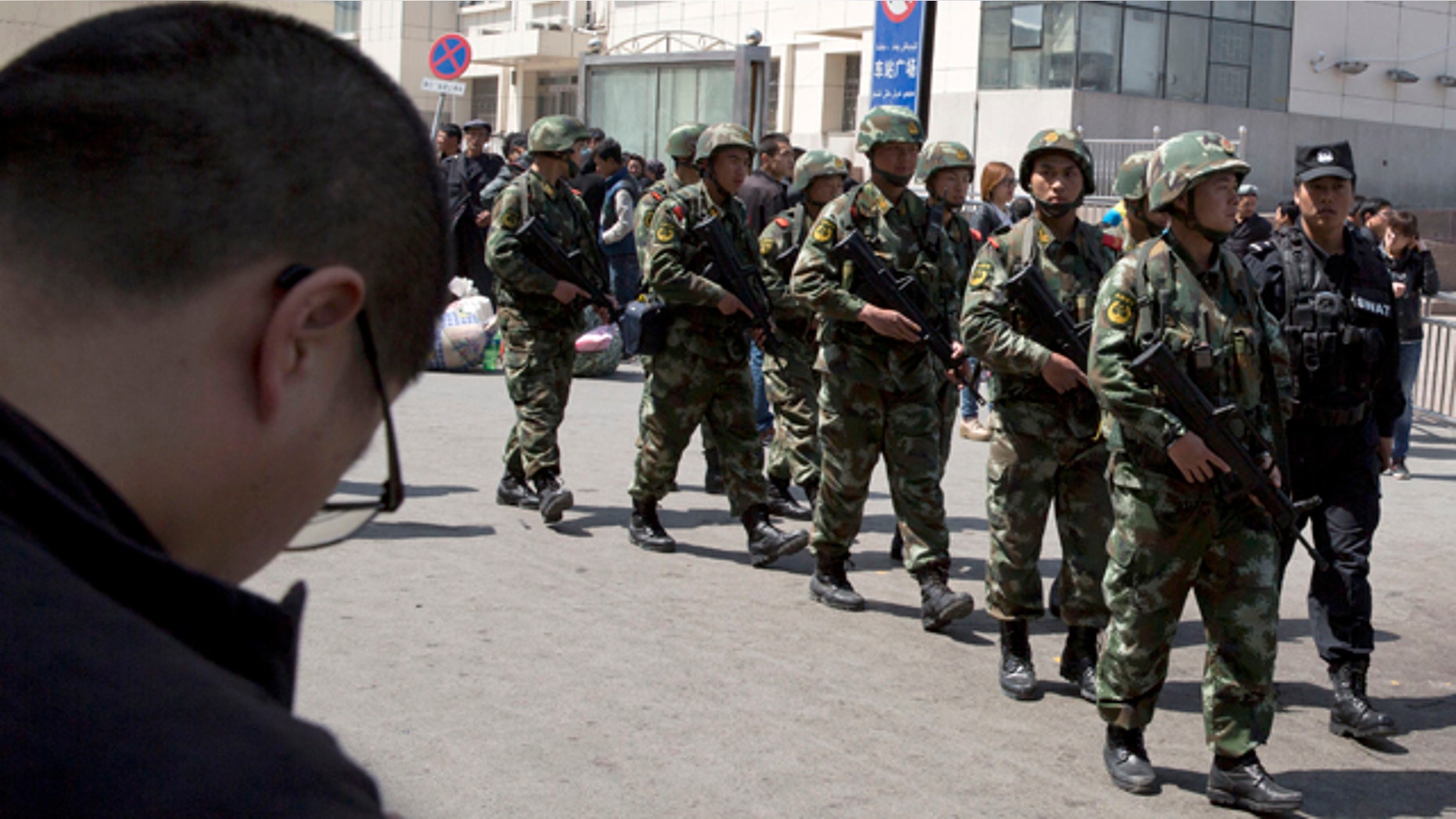 May 1, 2014: Heavily armed Chinese paramilitary policemen march past the site of Wednesday's explosion outside the Urumqi South Railway Station in Urumqi in northwest China's Xinjiang Uygur Autonomous Region. (AP Photo/Ng Han Guan)