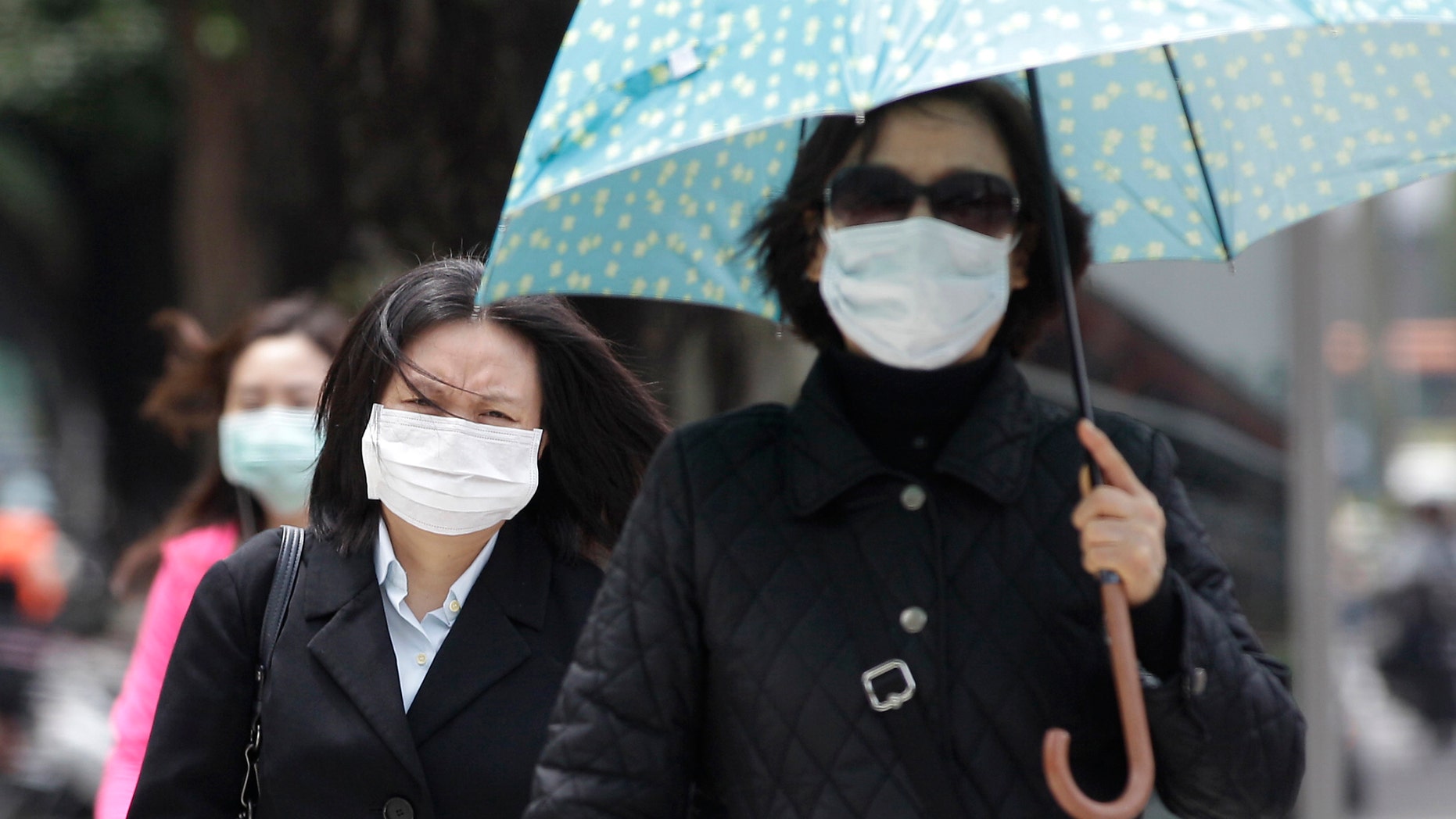 Pedestrians wearing medical masks walk on the street outside National Taiwan University Hospital in Taipei.