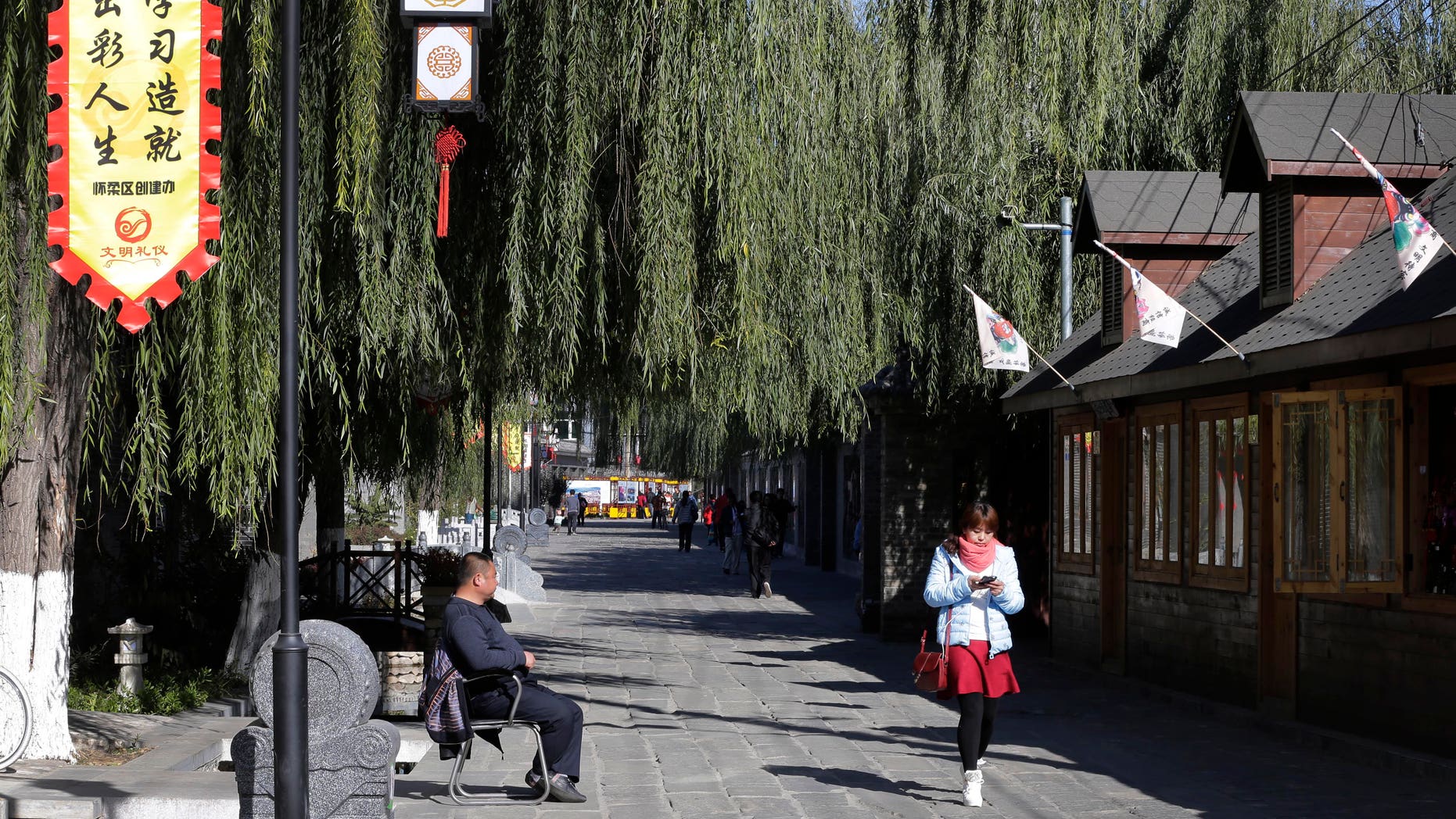 Nov. 9, 2014 - FILE photo of woman walking past a shop in Huairou district where the g Asia-Pacific Economic Cooperation (APEC) summit met in Beijing, China. For the first time in decades, the U.S. is no longer the largest economy in the world, and China has become number one.