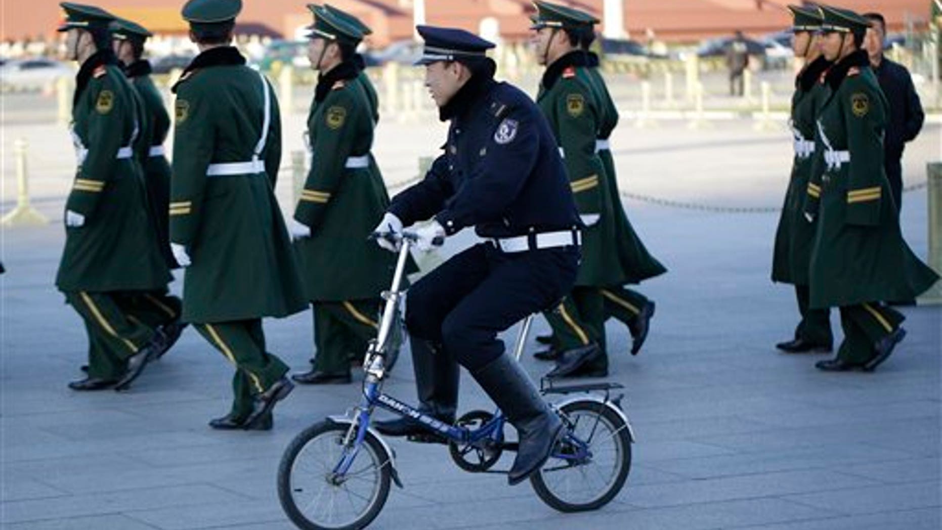 Nov. 13, 2012: Chinese paramilitary policemen march as police officer rides a bicycle during the 18th Chinese Communist Party Congress in Tiananmen Square.