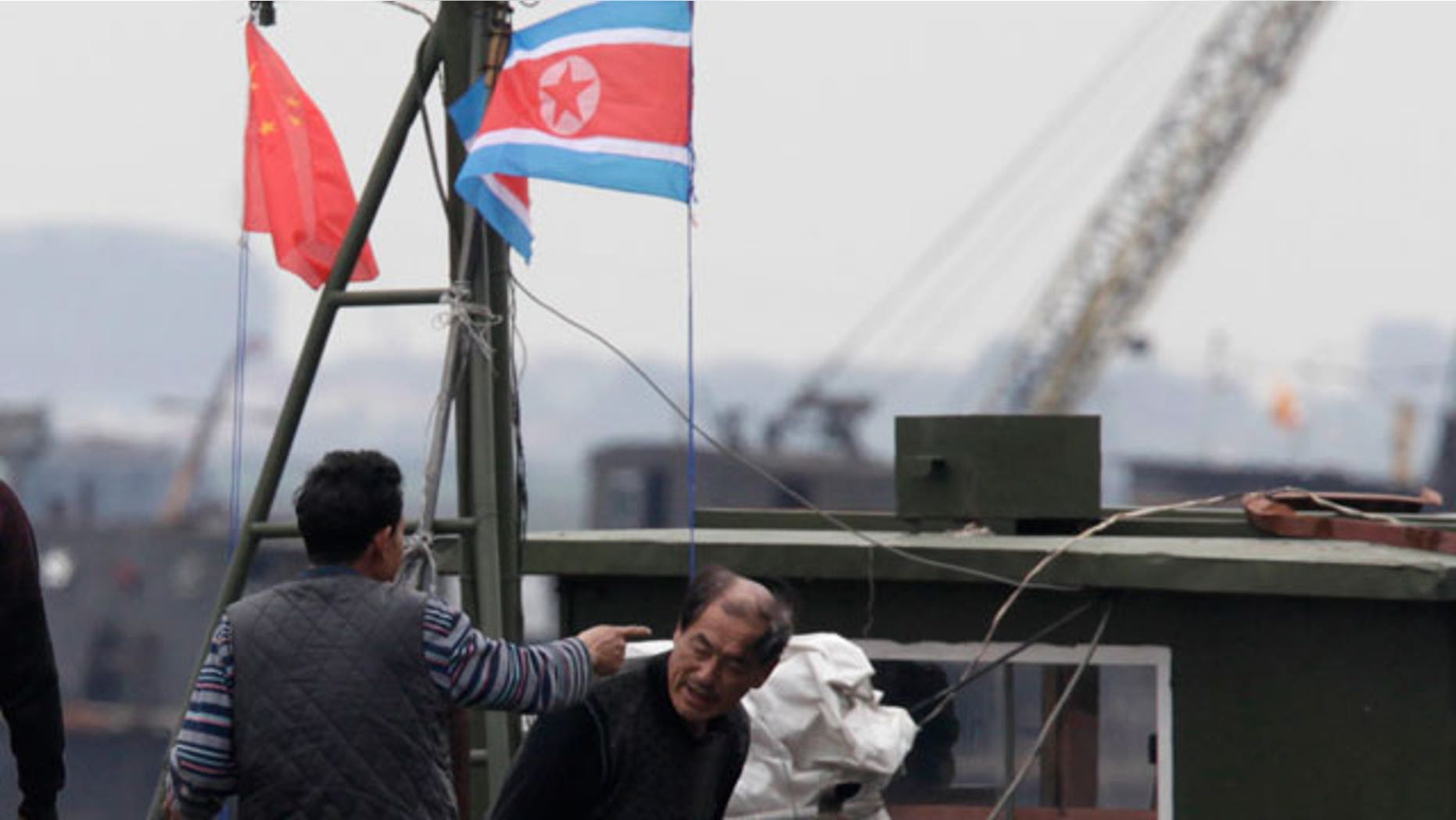 A man gestures towards another onboard a boat marked with both Chinese and North Korean flags along the Yalu river near Dandong in northeastern China's Liaoning province on Saturday, May 29, 2010. Top South Korean military commanders in Seoul discuss how to counter North Korean provocations as the leaders of South Korea, China and Japan head to the South Korean southern island of Jeju for a summit expected to focus on the sinking of a warship blamed on North Korea.