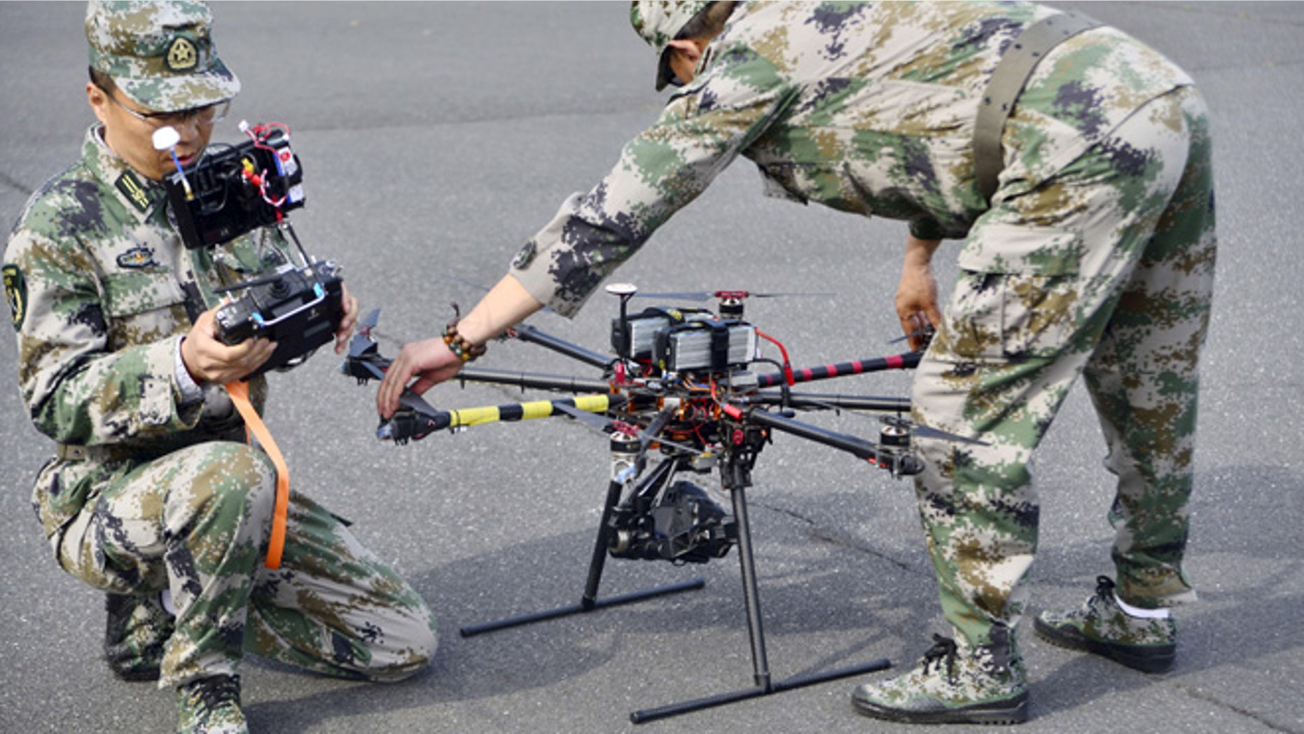 April 21, 2015: A pair of militia members prepare to fly drones during a test in Shanghai, China.