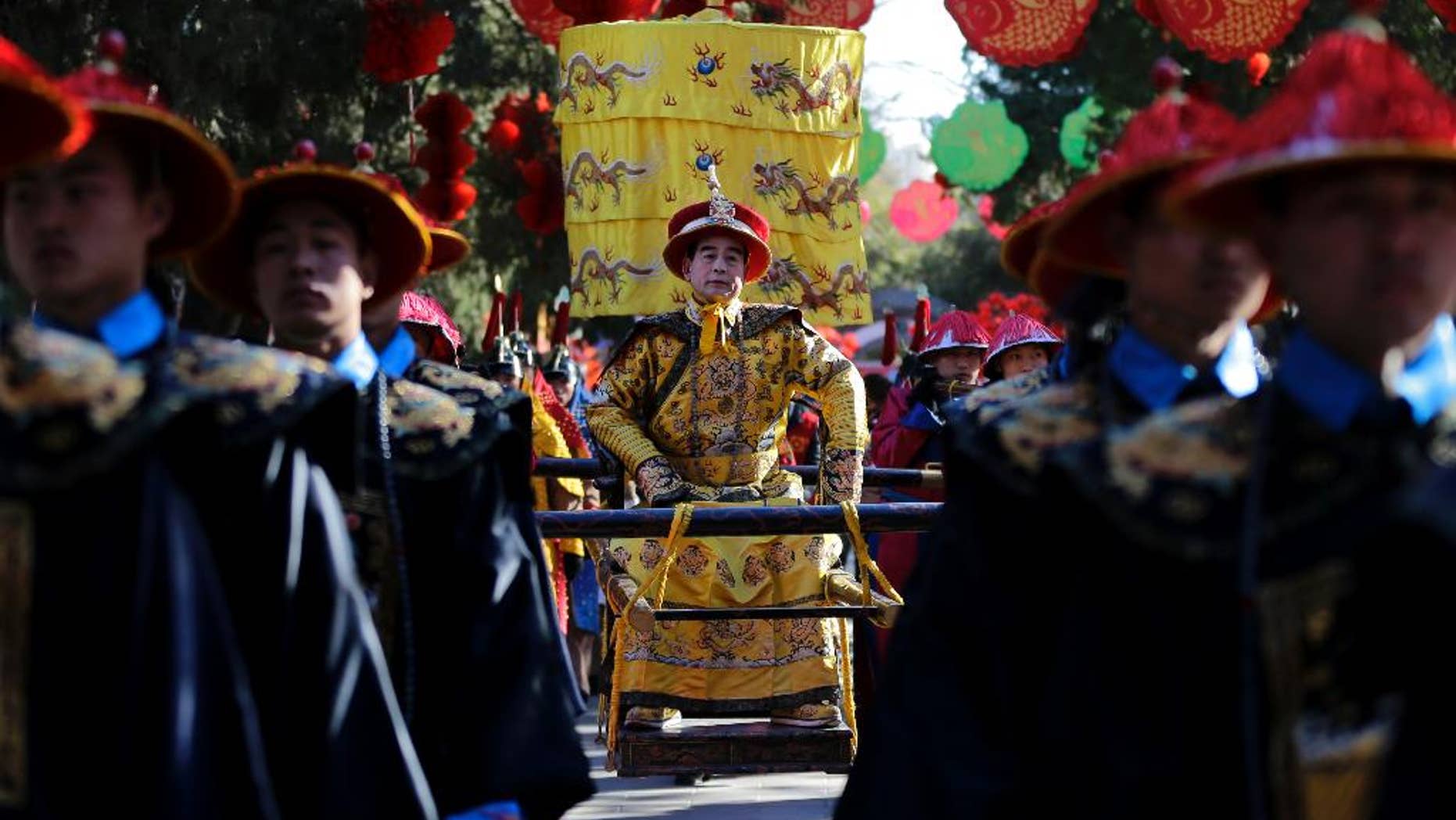 In this photo taken Wednesday, Feb. 18, 2015, Qi Xue’en, a performer dressed as a Qing Dynasty emperor, seated at center, is carried during a re-enactment of an ancient sacrificial ceremony at Beijing’s Ditan Park, the “Altar of the Earth,” on the eve of the Lunar New Year. Ditan Park is one of four altars dedicated to worship of the natural elements under the principles of Chinese cosmology and geomancy, popularly known as feng shui. During the seven-day Lunar New Year holiday, the parks throng with visitors shopping for festive goods, joining in carnival games and taking a break from hectic modern life. “I have been playing the part of emperor since 1990. I have two apprentices and several pupils now,” Qi, 58, said. “Today and tomorrow, I will play the part of emperor, so I can send New Year’s greetings to people I know. Let the pupils play on the second and third days of the Lunar New Year. I am getting old.” (AP Photo/Andy Wong)