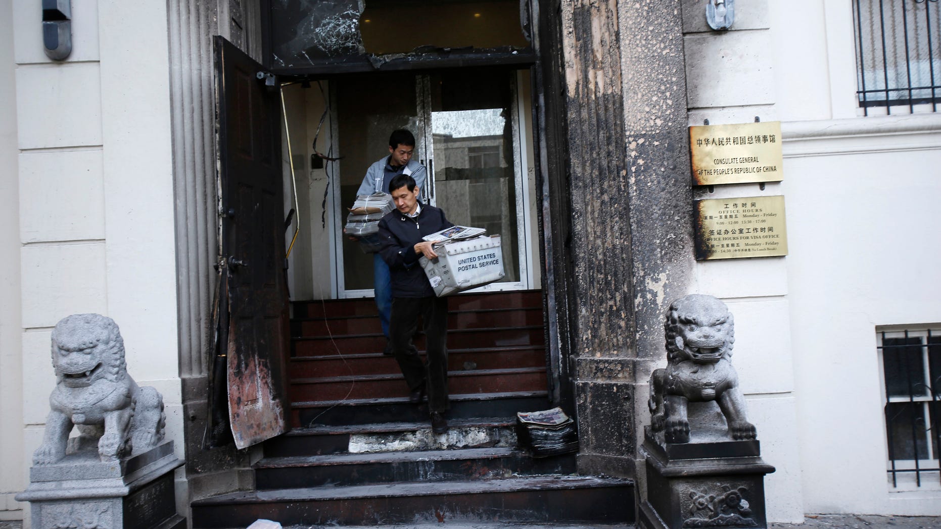 Jan. 2, 2014: Workers carry stacks of newspaper from the steps of the damaged front of the Chinese consulate after an unidentified person set fire to the main gate in San Francisco, California.