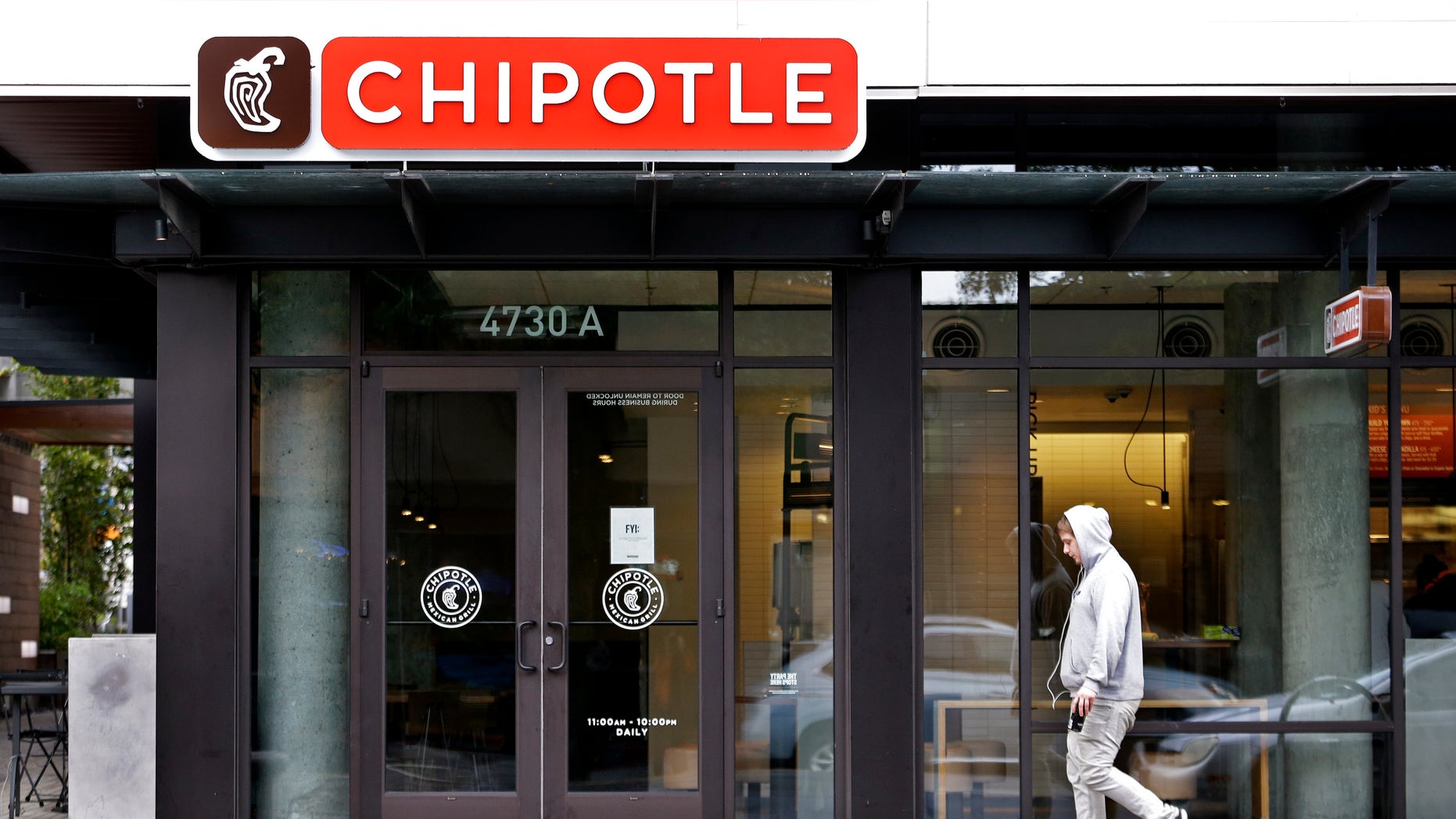 A pedestrian walks past a closed Chipotle restaurant Monday, Nov. 2, 2015, in Seattle. An E. coli outbreak linked to Chipotle restaurants in Washington state and Oregon has sickened nearly two dozen people in the third outbreak of foodborne illness at the popular chain this year. Cases of the bacterial illness were traced to six of the fast-casual Mexican food restaurants, but the company voluntarily closed down 43 of its locations in the two states as a precaution. (AP Photo/Elaine Thompson)