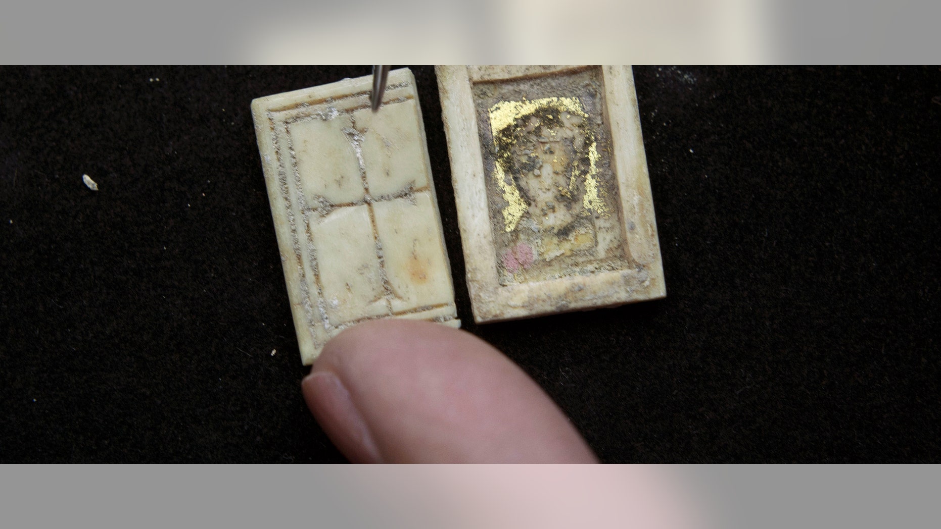Un restaurador de la Autoridad de Antigüedades de Israel muestra una diinuta caja cristiana bizantina hecha de hueso, con una cruz labrada en la tapa, en Jerusalén, el domingo, 30 de octubre del 2011. El objeto muy probablemete era llevado por un creyente que lo perdiò en una de las calles de la ciudad alrededor del siglo VI, dijeron arqueólogos.(Foto AP/Sebastian Scheiner)