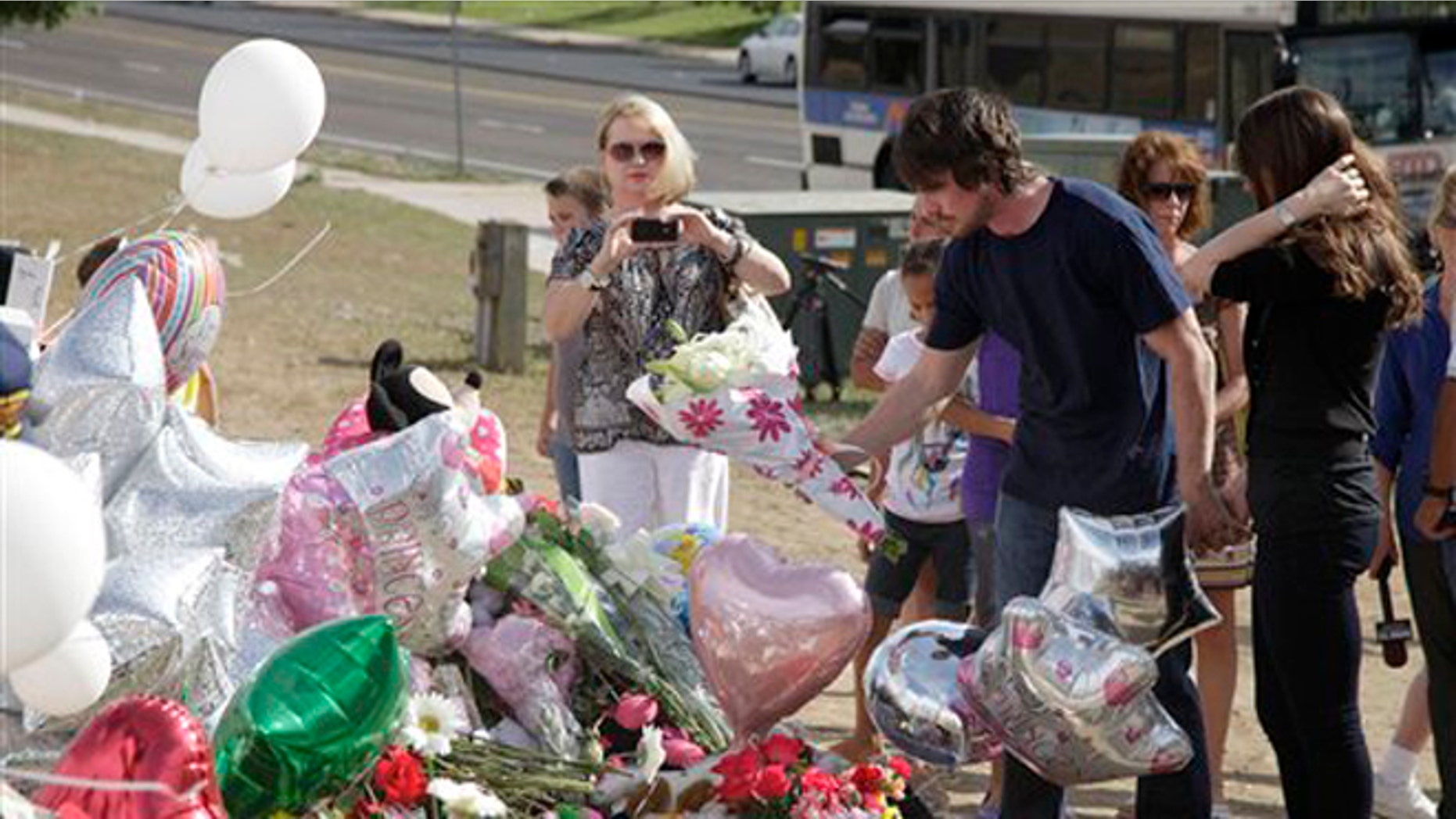 July 24, 2012: Actor Christian Bale, second right, and his wife Sibi Blazic, right, place flowers on a memorial to the victims of Friday's mass shooting in Aurora, Colo.