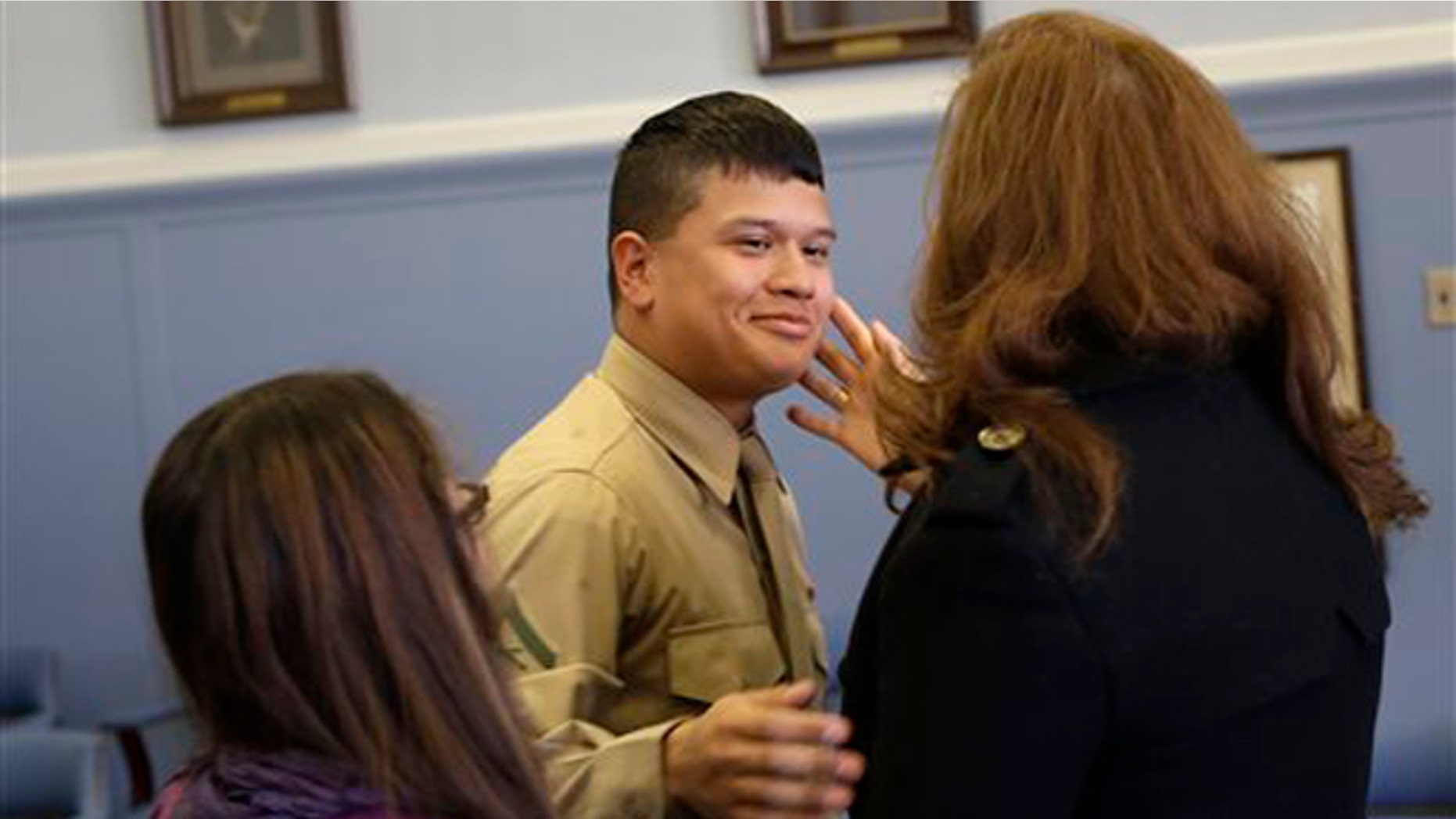 Lance Cpl. Christopher Mohedano-Hernandez, center, is hugged by family members after participating in an adoption ceremony in Mineola, N.Y., Tuesday, Dec. 24, 2013. The U.S. Marine home on leave has been formally adopted by his stepfather in a Christmas Eve adoption ceremony held in a suburban New York courtroom. Mohedano-Hernandez is the latest in what experts call a growing trend of adult adoptions. (AP Photo/Seth Wenig)