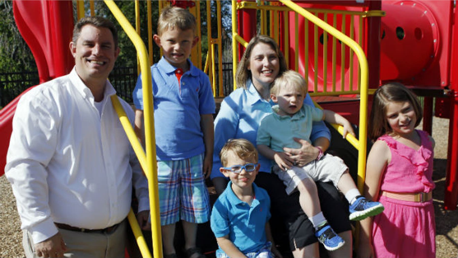 In this May 29, 2014 photo, Christy Wolford holds her youngest son Lucas, 2, as her husband Bubba and other children Lauren, 8, Alexander, 4, and Everett, 3, are pictured at the Primrose School the couple runs in Fort Collins, Colo. Christy Wolford's ovaries were suppressed during cancer treatment and she has had three boys since it ended in 2006. (AP Photo/Ed Andrieski)