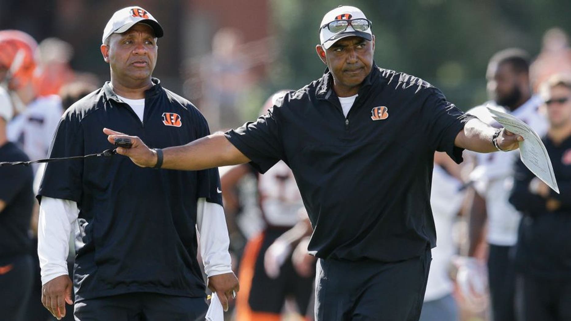 Cincinnati Bengals coach Marvin Lewis, right, signals to his players alongside offensive coordinator Hue Jackson, left, during a joint NFL football training camp with the New York Giants, Wednesday, Aug. 12, 2015, in Cincinnati. (AP Photo/John Minchillo)
