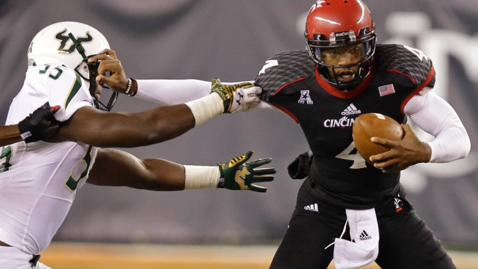 FILE - In this Oct. 24, 2014, file photo, Cincinnati quarterback Munchie Legaux (4) is sacked by South Florida linebacker Josh Black (55) during the second half of an NCAA college football game in Cincinnati. Gunner Kiel reaggravated his ribs, leaving it up to Legaux to pull Cincinnati through. It worked against South Florida (AP Photo/Al Behrman, File)