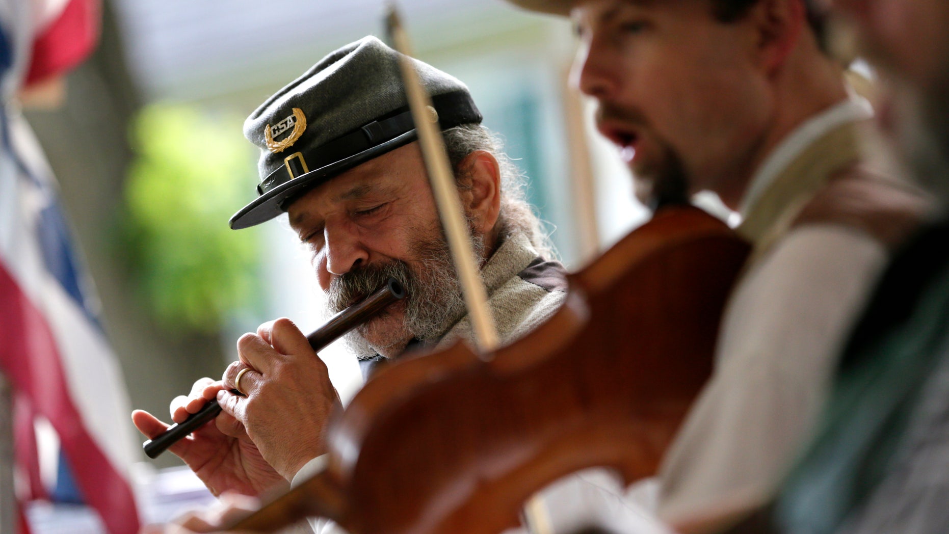 In this June 16, 2012 photo, Greg Hernandez plays a fife during a performance with the 2nd South Carolina String Band in Hagerstown, Md. Some re-enactors have formed camp bands to play music that soldiers enjoyed hearing around battlefield campfires. The most popular tunes included songs from the minstrel stage. Groups such as the 2nd South Carolina String Band pride themselves on their accurate impressions right down to the exaggerated black dialect of songs with inescapably racist overtones. (AP Photo/Patrick Semansky)