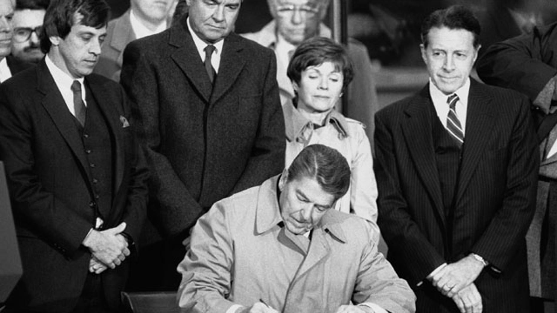 FILE: President Ronald Reagan signs the papers accepting the Vietnam Veterans Memorial for the United States government during ceremonies in Washington. With the President are: Jan Scruggs, President of the Memorial Fund, Interior Secretary William Clark and his wife, and Defense Secretary Caspar Weinberger.