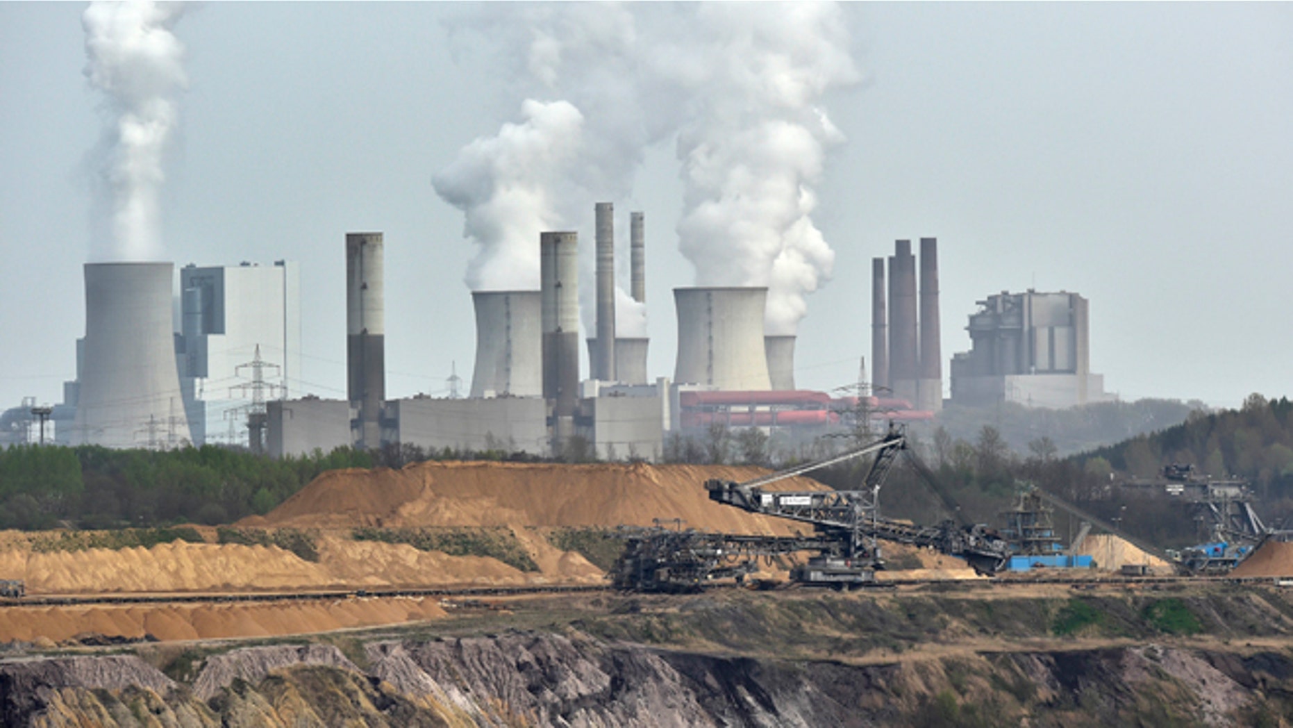 FILE - In this April 3, 2014 file photo giant machines dig for brown coal at the open-cast mining Garzweiler in front of a smoking power plant near the city of Grevenbroich in western Germany. The U.N.s expert panel on climate change is preparing a new report this weekend outlining the cuts in greenhouse gases, mainly CO2 from the burning of fossil fuels, required in coming decades to keep global warming in check. (AP Photo/Martin Meissner, File)