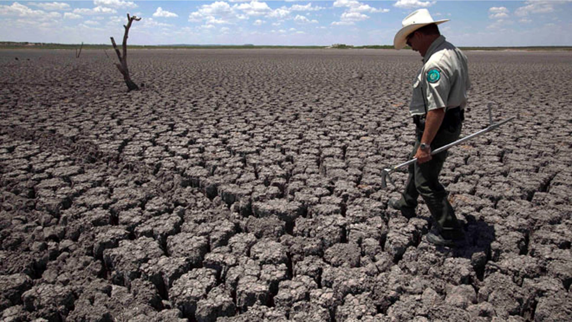 Aug. 3, 2011, file photo of Texas State Park police officer Thomas Bigham walking the cracked lake bed of O.C. Fisher Lake in San Angelo, Texas.