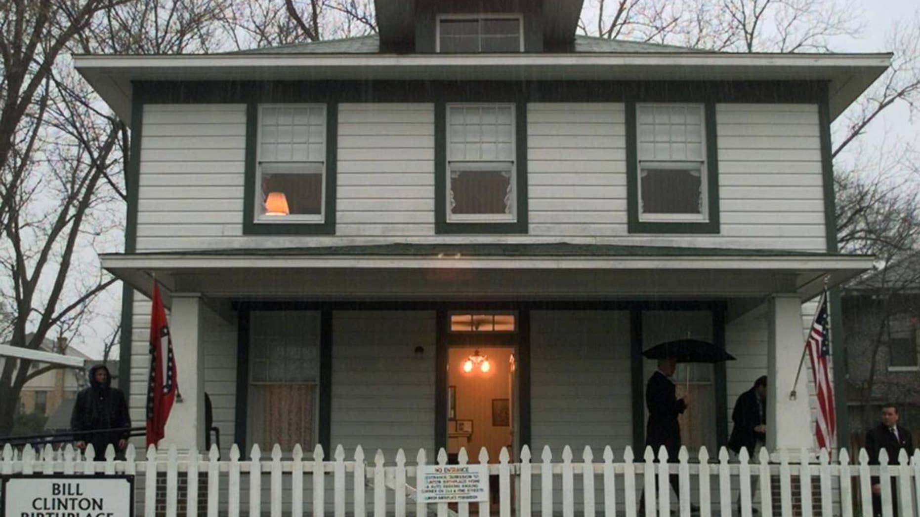 FILE - In this March 12, 1999 file photo, President Bill Clinton holds an umbrella under the porch of his childhood home in Hope, Ark. The Clinton First Home Museum in Hope will display the trappings of its new status as a national historic site come the first of the year. The museum opened in 1997 and has been run by a private foundation since then. (AP Photo/Khue Bui, File)