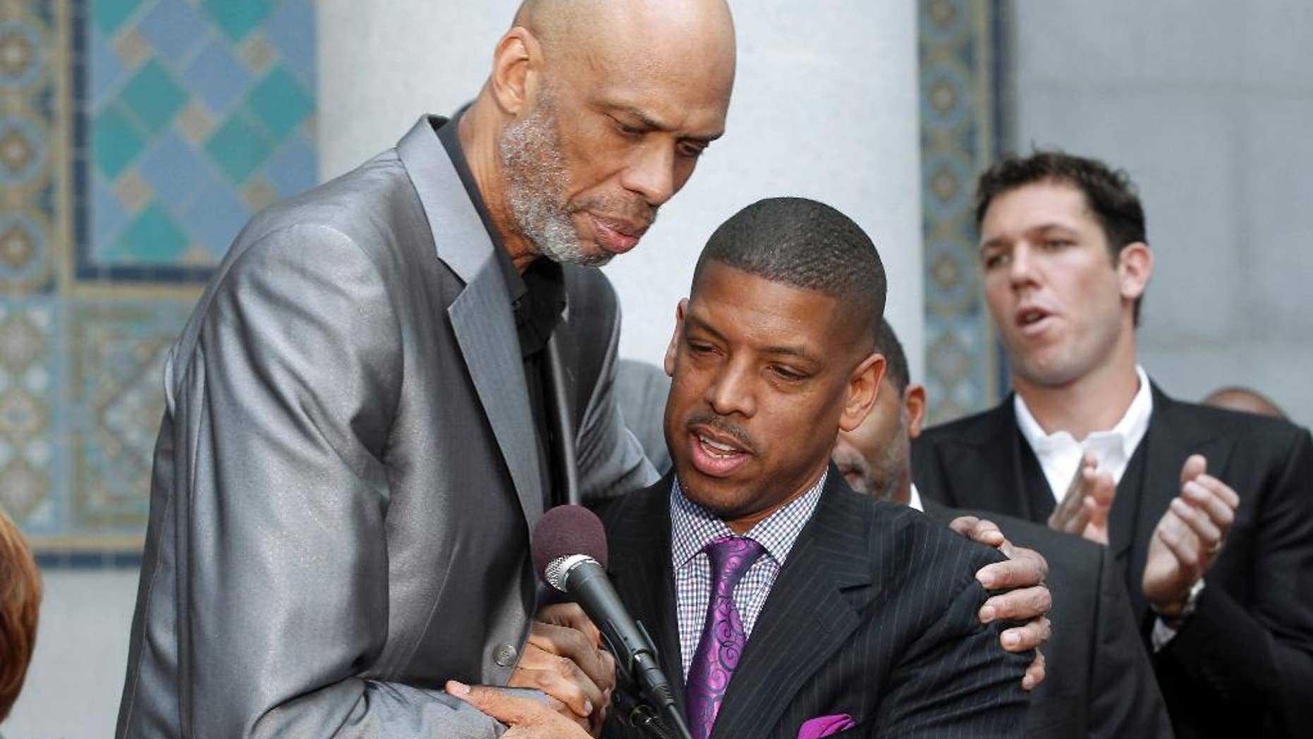 Sacramento, Calif., Mayor Kevin Johnson, center, and Hall of Famer Kareem Abdul-Jabbar embrace during a news conference outside City Hall in Los Angeles Tuesday, April 29, 2014, after Johnson's comments on the decision by NBA commissioner Adam Silver to ban Los Angeles Clippers owner Donald Sterling from basketball for life in response to racist comments the league says Sterling made in a recorded conversation. Former NBA player Luke Walton applauds at rear right rear. (AP Photo)