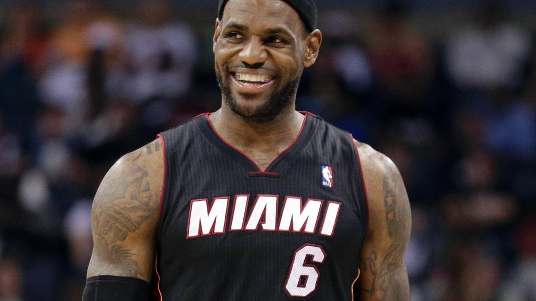 FILE - In this April 28, 2014, file photo, Miami Heat's LeBron James smiles as he walks down the court during the second half in Game 4 of an opening-round NBA basketball playoff series against the Charlotte Bobcats in Charlotte, N.C. "Commissioner Silver thank you for protecting our beautiful and powerful league!! Great leader!! #BiggerThanBasketball #StriveForGreatness," James wrote on Twitter Tuesday, April 29, 2014, after Silver announced that Los Angeles Clippers owner Donald Sterling has been banned for life by the league, in response to racist comments the league says he made in a recorded conversation. (AP Photo/Chuck Burton, File)