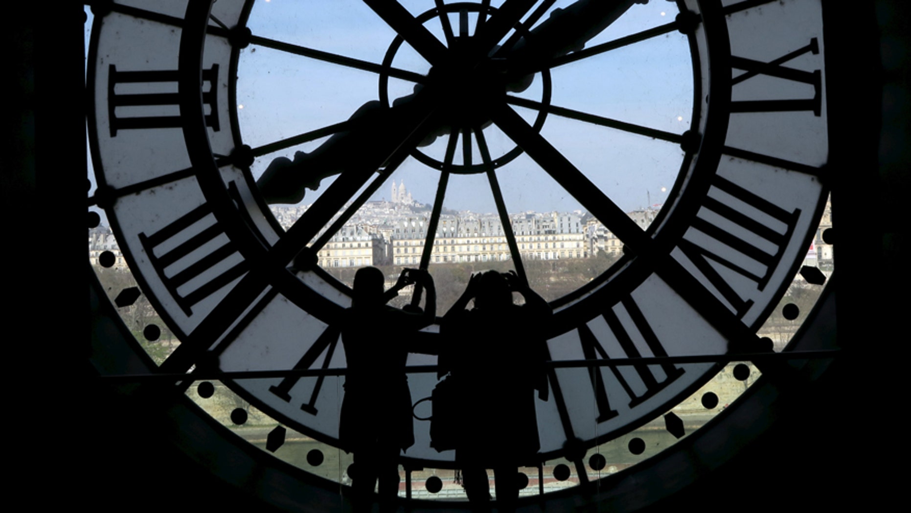 File photo - Visitors at the Musee d'Orsay are seen in silhouette as they take pictures from behind a giant clock face April 8, 2015.
