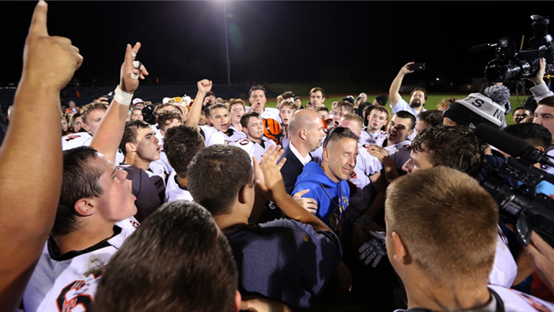 Oct. 16, 2015: Bremerton assistant football coach Joe Kennedy, in blue, is surrounded by Centralia players after they took a knee with him and prayed after their game against Bremerton, in Bremerton, Wash. (Meegan M. Reid/Kitsap Sun via AP)