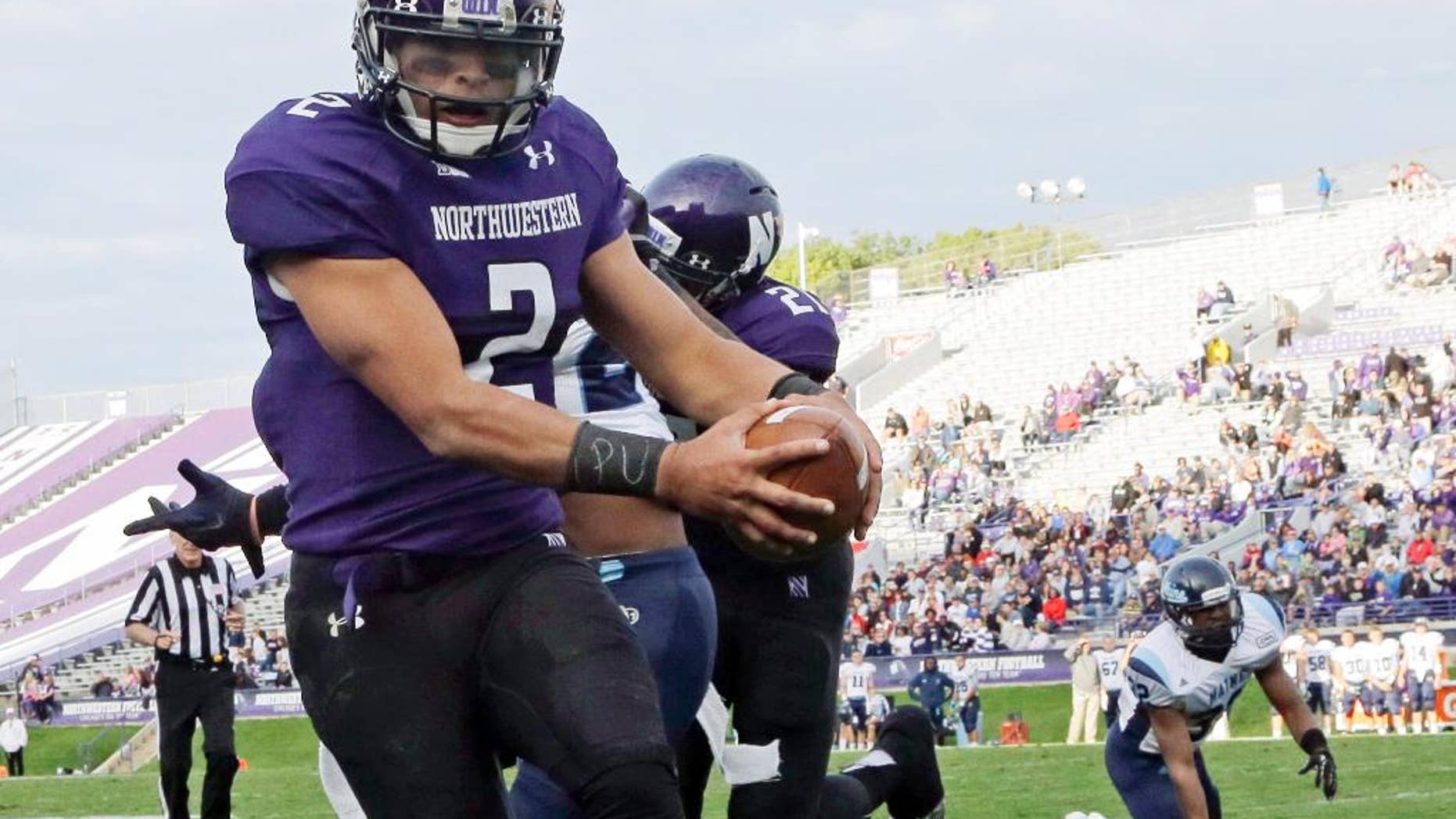 FILE - In this Sept. 21, 2013 file photo, Northwestern quarterback Kain Colter (2), wears APU for "All Players United" on wrist tape as he scores a touchdown during an NCAA college football game against Maine in Evanston, Ill. The decision to allow Northwestern football players to unionize raises an array of questions for college sports. Among them, state schools vs. public schools, powerhouse programs vs. smaller colleges. (AP Photo/Nam Y. Huh, File)