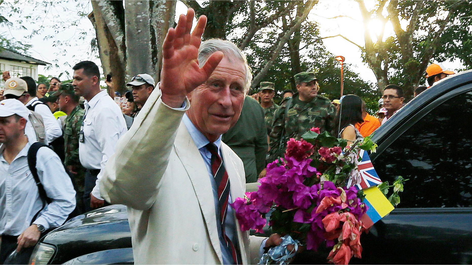 Britain's Prince Charles, right, waves towards local residents as he holds a bouquet of flowers that was given to him during a visit to La Macarena, Colombia, Thursday, Oct. 30, 2014. Prince Charles and his wife Camilla are in Colombia as part of a nine-day tour of Latin America. (AP Photo/Fernando Vergara)