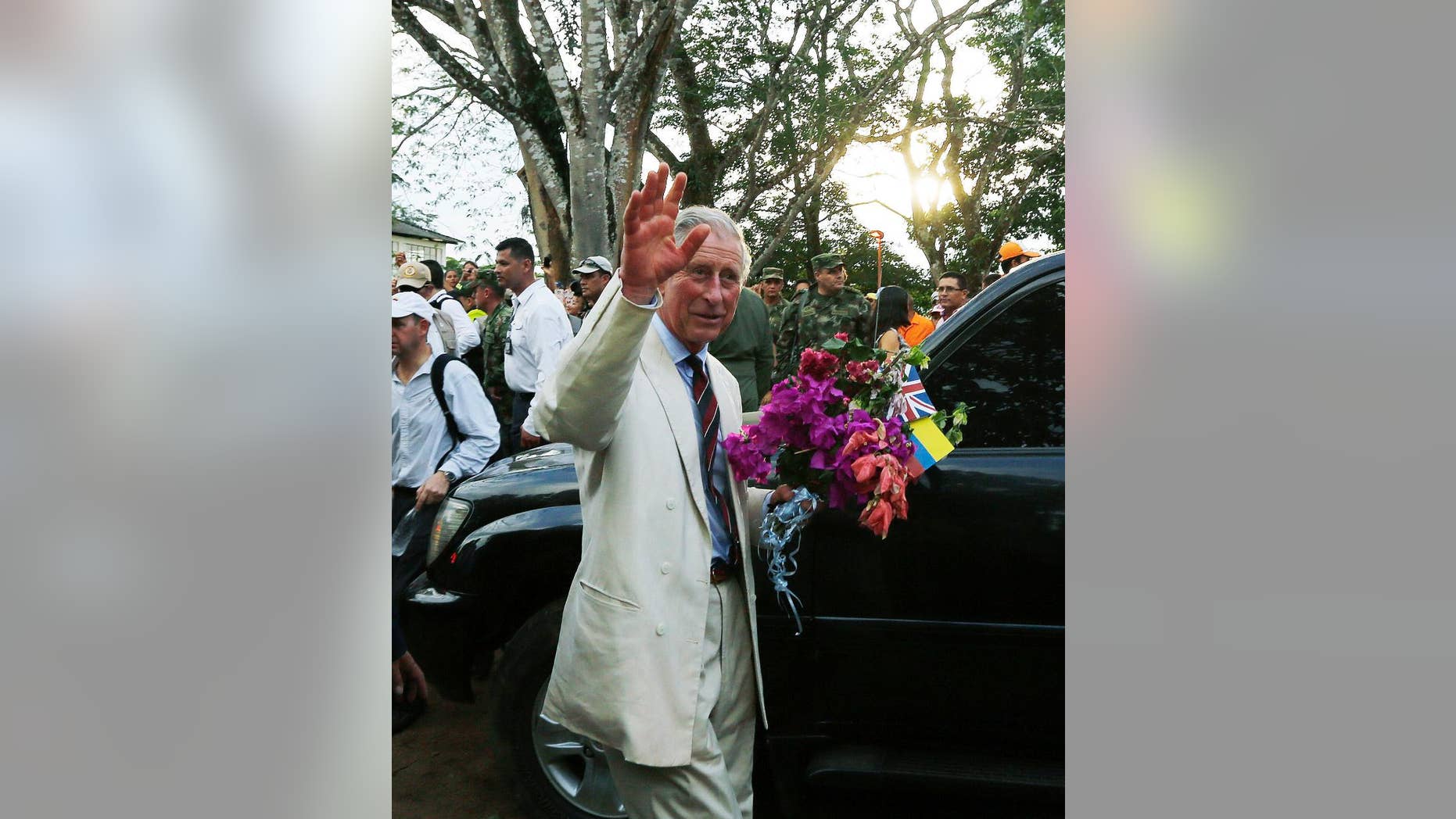 Britain's Prince Charles, right, waves towards local residents as he holds a bouquet of flowers that was given to him during a visit to La Macarena, Colombia, Thursday, Oct. 30, 2014. Prince Charles and his wife Camilla are in Colombia as part of a nine-day tour of Latin America. (AP Photo/Fernando Vergara)