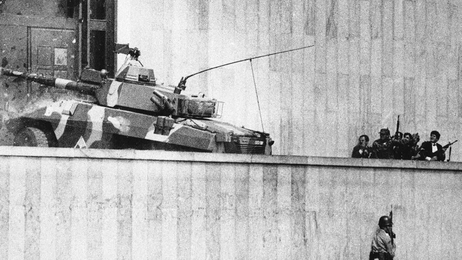 FILE - In this Nov. 6, 1985, file photo, an armored vehicle crashes through the two story wooden doors at the front entrance to the Palace of Justice in Bogota, as soldiers and policemen prepared to rush inside. The Inter-American Court of Human Rights has charged Colombia, Wednesday Dec. 10, 2014, with human rights violations in connection with the disappearance of 10 people in 1985’s hostage crisis at the Supreme Court. The court ordered Colombia to provide relatives with compensation and psychological assistance, publish its sentence in national news media, and continue investigating the case. In addition to those disappeared, more than 100 people were killed in the government operation to retake the building, including all rebels and many judges. (AP Photo/Carlos Gonzalez, File)
