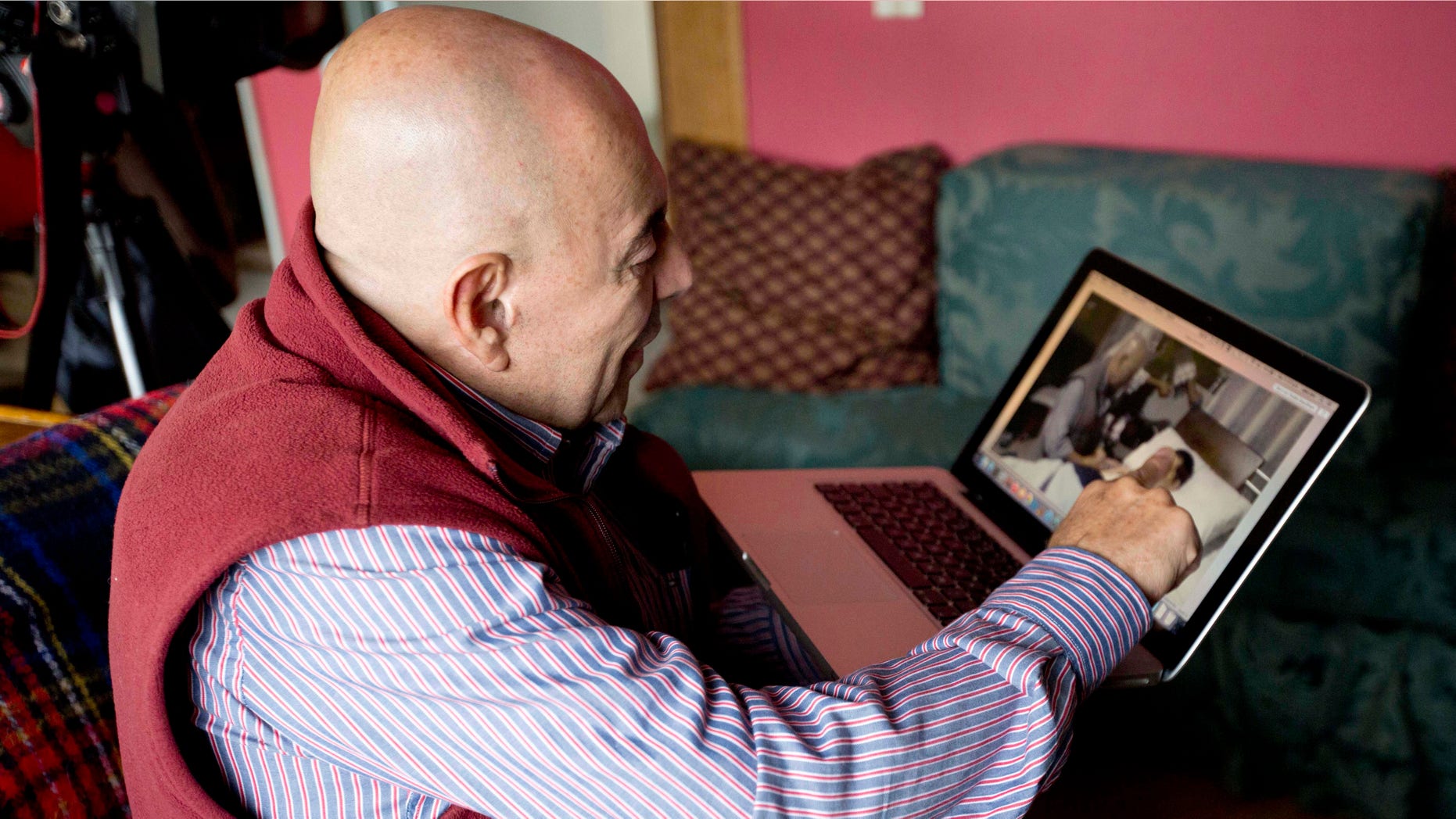 In this June 19, 2015 photo, Dr. Gustavo Quintana, who helps people with terminal illnesses end their lives, points to a video that shows him with a patient, as he speaks during an interview in Bogota, Colombia. Quintana says barely a week goes by without him receiving a phone call from a desperate patient or family member looking to end their agony. He claims to have helped more sick people die than the late Jack Kevorkian. (AP Photo/Fernando Vergara)