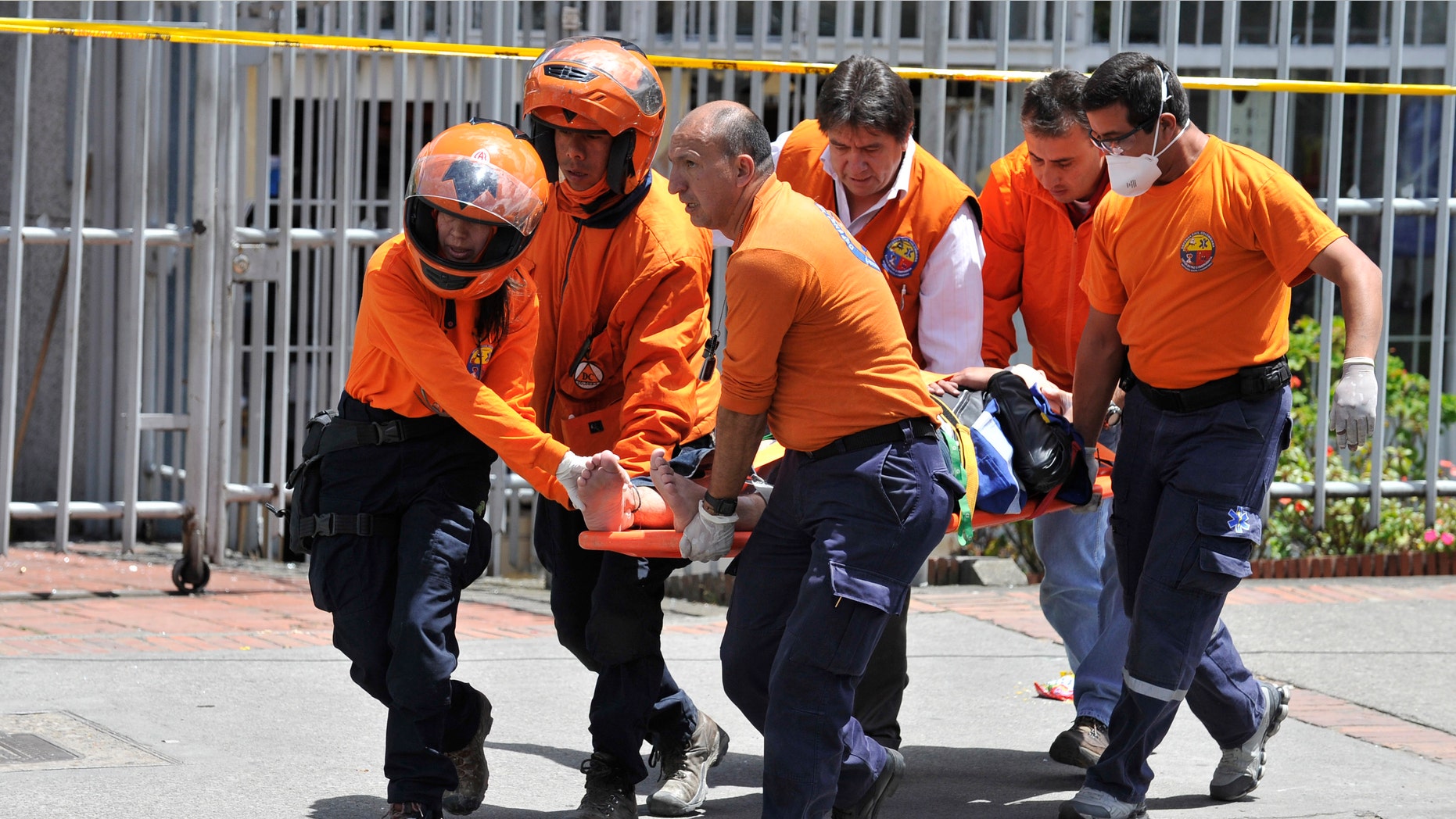 Rescue workers carry an injured person after a bomb explosion in Bogota, Colombia, Tuesday, May 15, 2012. A bomb targeting former Colombian interior minister Fernando Londono killed two of his bodyguards and injured at least 31 others in the heart of Bogota's uptown commercial district, authorities said. (AP Photo/Carlos Julio Martinez)