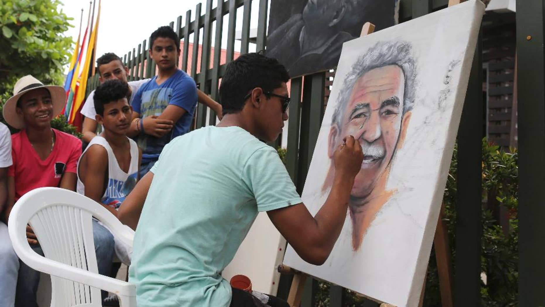 Friends surround Melquin Merchan, an 18-year-old painter from Aracataca, as he paints a portrait of Gabriel Garcia Marquez in front of the house where the Nobel laureate was born in Aracataca, Colombia, Friday, April 18, 2014. Garcia Marquez died at the age of 87 in Mexico City on Thursday. (AP Photo/Ricardo Mazalan)