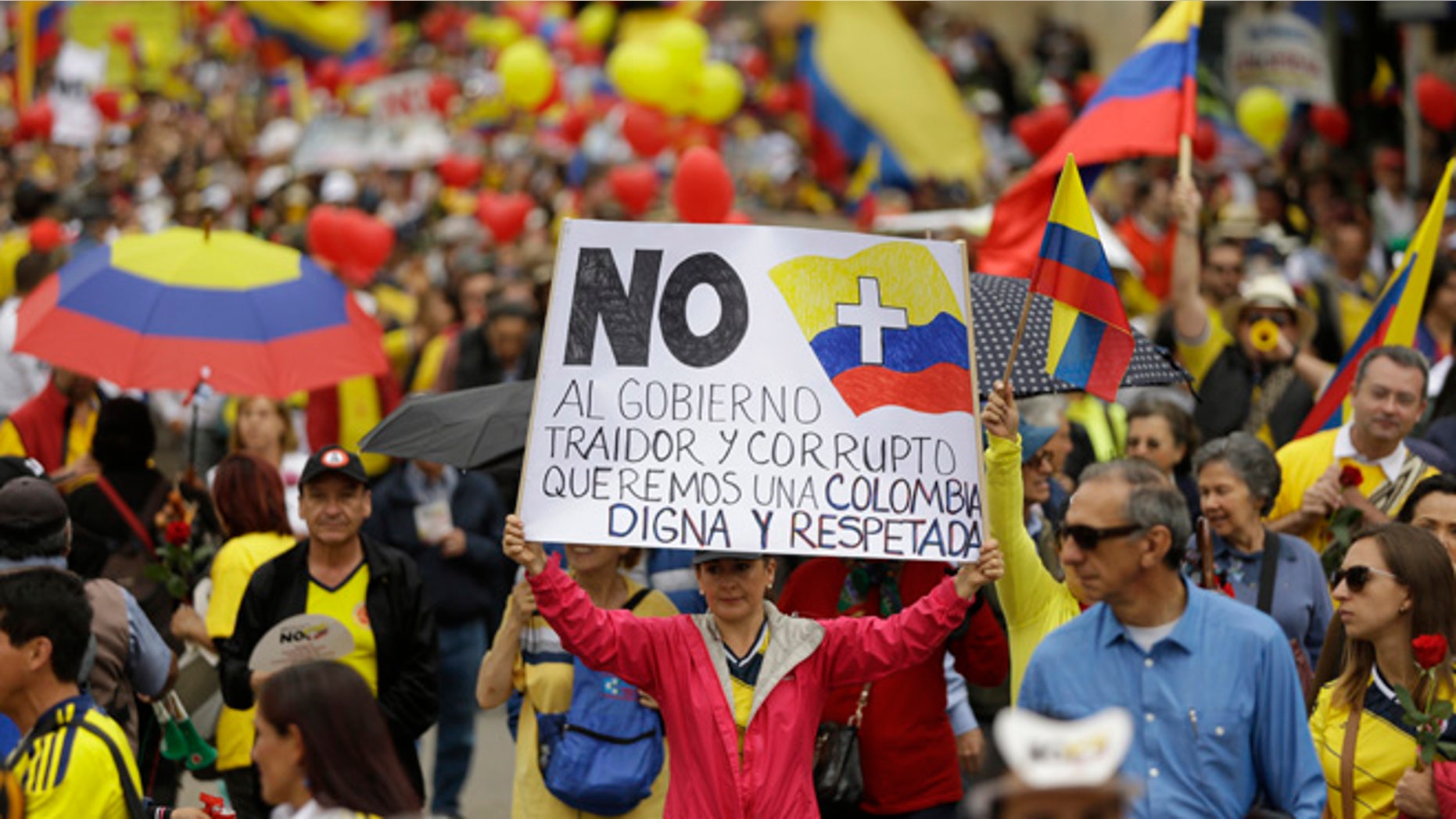 Colombians march to protest against President Juan Manuel Santos' government and denounce the concessions the government has made in peace talks with the Revolutionary Armed Forces of Colombia, or FARC, in Bogota, Colombia, Saturday, April 2, 2016. The message on the poster at center reads in Spanish; "No more to a traitorous and corrupt government. We want a dignified and respected Colombia." (AP Photo/Fernando Vergara)