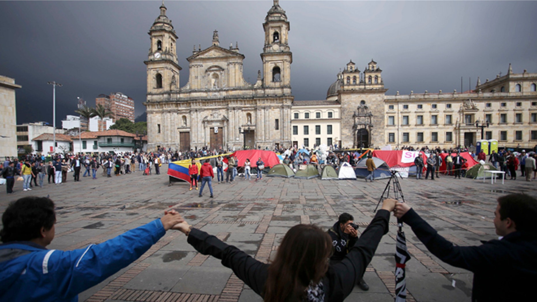 Demonstrators hold hands to support a peace accord between the Colombian government and rebels of the Revolutionary Armed Forces of Colombia, FARC, at the main square in Bogotá, Colombia, Saturday, Oct. 8, 2016. Dozens of people are camping at the Bolívar square in support of the peace process. Voters narrowly rejected in a referendum a peace accord signed between President Juan Manuel Santos and the FARC. (AP Photo/Ivan Valencia)