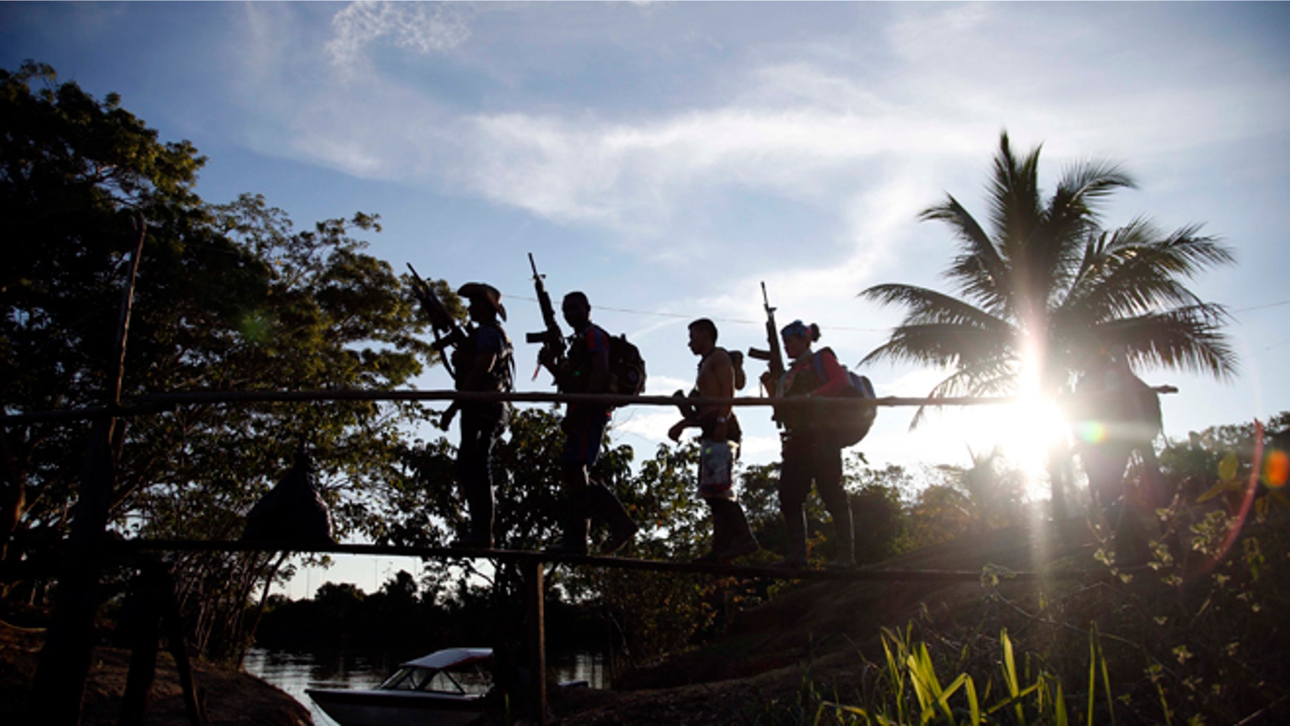 In this Aug. 12, 2016 photo, rebels of the 48th Front of the Revolutionary Armed Forces of Colombia walk on a makeshift footbridge in the southern jungles of Putumayo, Colombia. (AP Photo/Fernando Vergara)