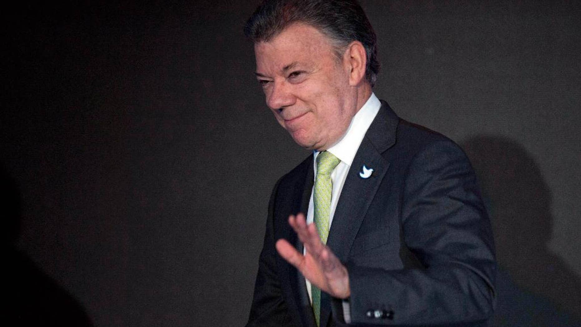 FILE - In this April 10, 2015, file photo, Colombia's President Juan Manuel Santos waves after delivering his speech during the CEO Summit of the Americas in Panama City. Colombia’s president ordered,on Wednesday, April 15, 2015, the resumption of air raids on rebel camps after an attack by leftist guerrillas killed 11 soldiers and wounded 19, jeopardizing progress in two-year-old peace talks. (AP Photo/Moises Castillo, File)
