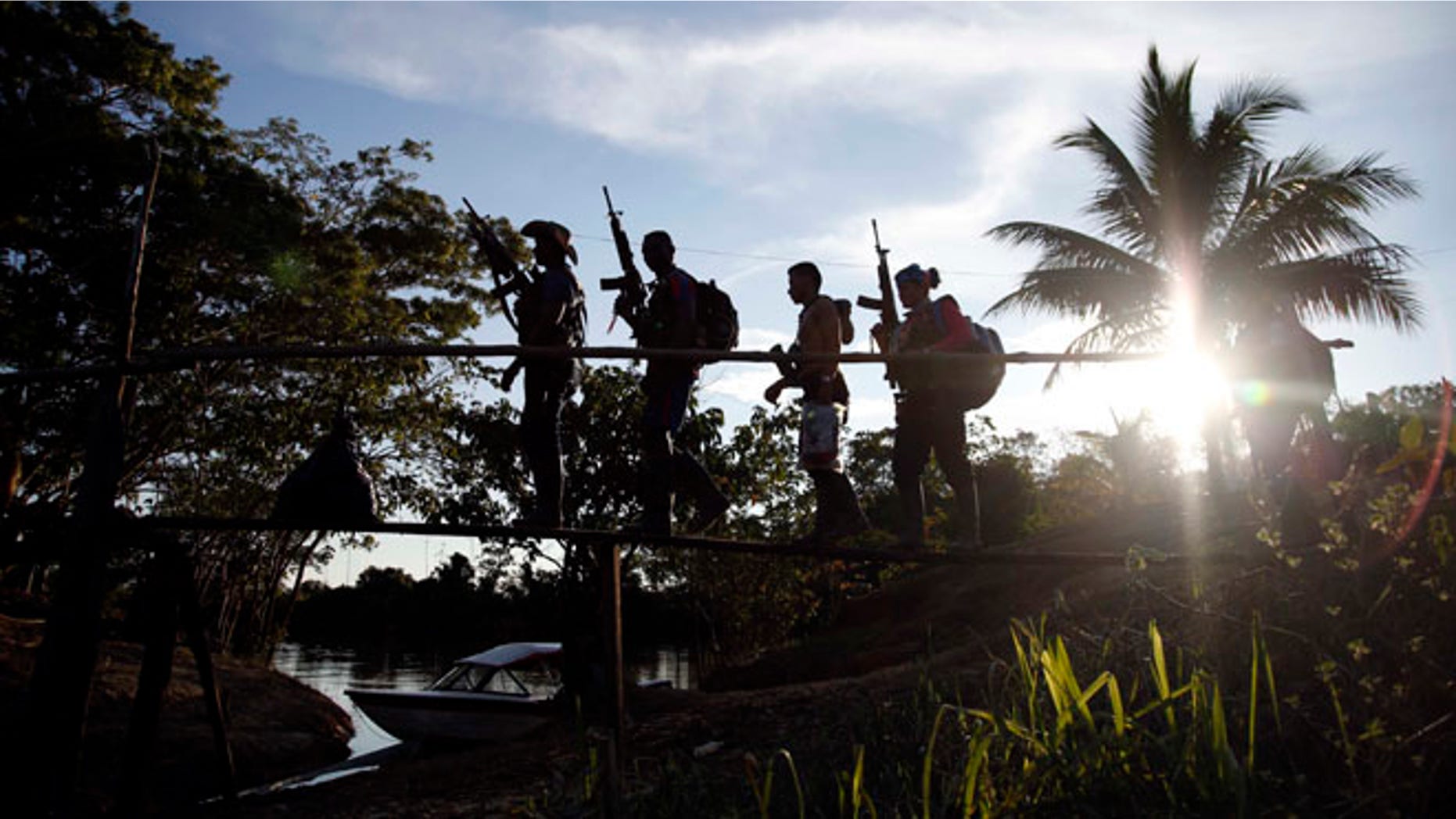 In this Aug. 12, 2016 photo, rebels of the 48th Front of the Revolutionary Armed Forces of Colombia walk on a makeshift footbridge in the southern jungles of Putumayo, Colombia. With the peace accords about to signed between the FARC and the governemt, gone are the days when they had to change camp every few days for fear of being stunned in their sleep by bombs falling from the skies. (AP Photo/Fernando Vergara)