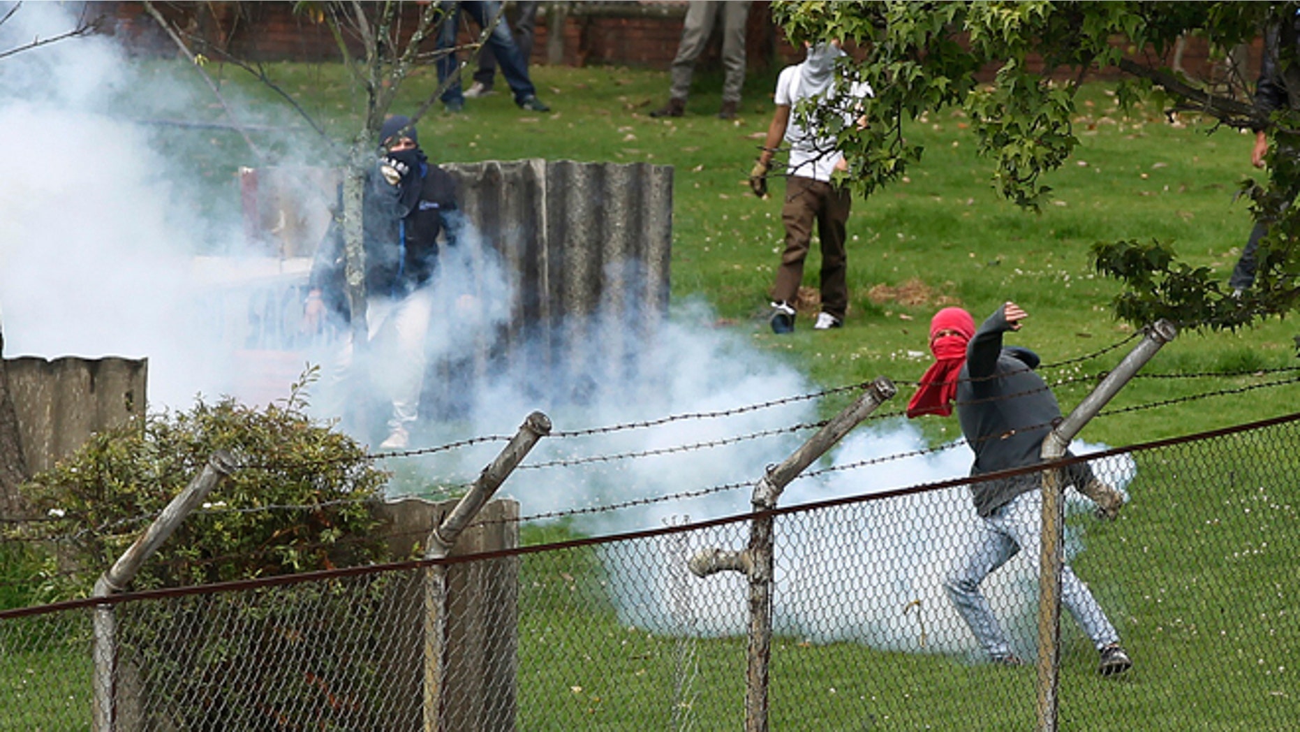 A university students motions to throw back a teargas canister at riot police during a protest in support of a national strike in Bogota, Colombia, Tuesday, Aug. 20, 2013. Truckers, coffee workers and health workers joined agricultural and mining workers in one of the largest national strikes ever faced by the Colombian government. The strikers demands include reduced gas prices and increased subsidies. (AP Photo/Fernando Vergara)