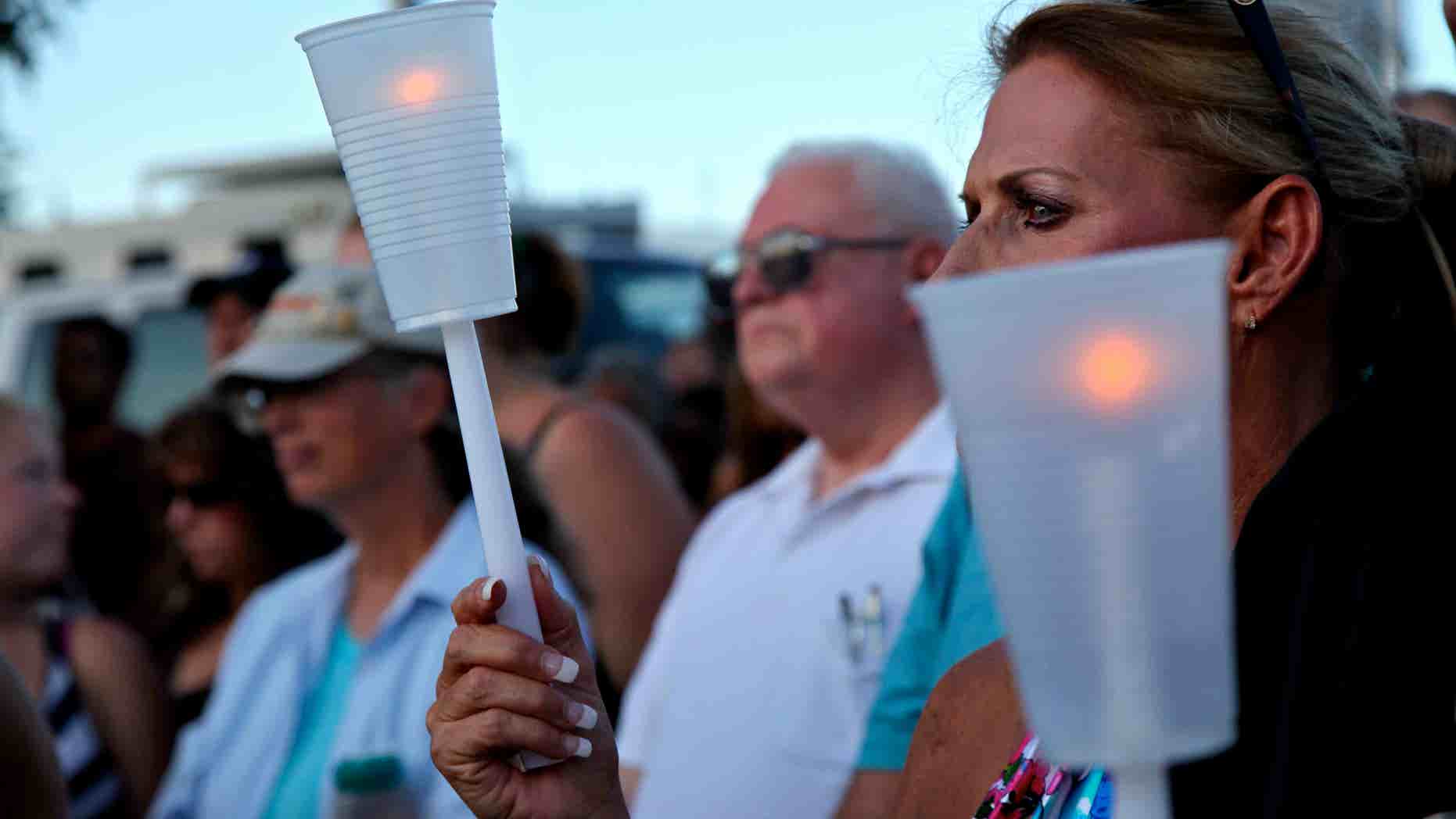 July 20, 2012: Less than 24 hours after 12 people were killed and dozens shot, Alicia Pervette stands across the street, holding a candle in memorial of the victims in Aurora, Colo.